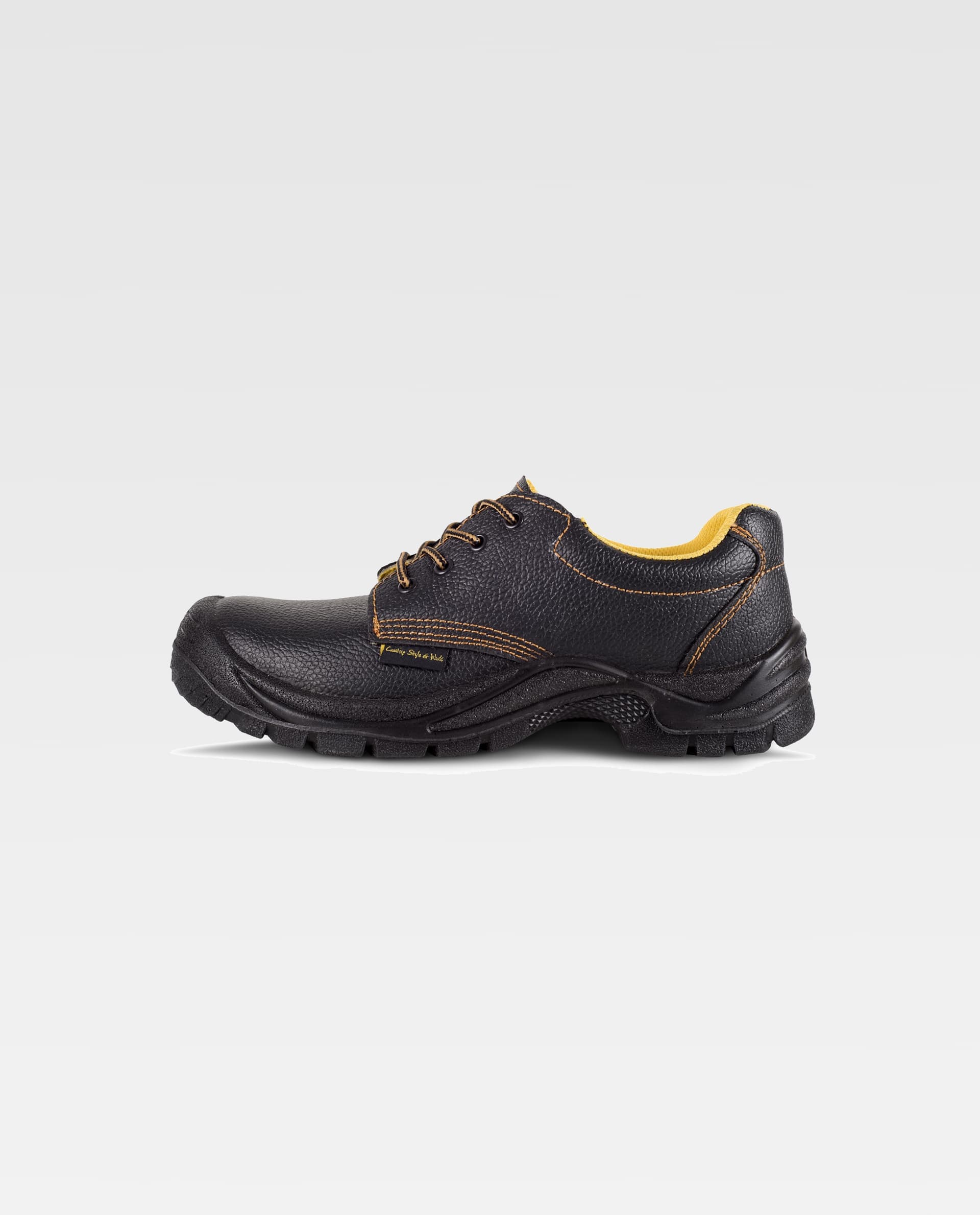 Zapato de seguridad negro de corte bajo con suela antideslizante y costuras naranjas sobre fondo blanco