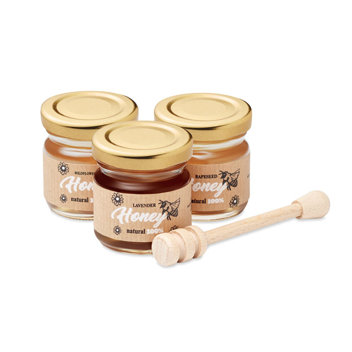 Tres tarros de miel natural (lavanda, brezo y colza) con tapa dorada y una cuchara de madera para servirla