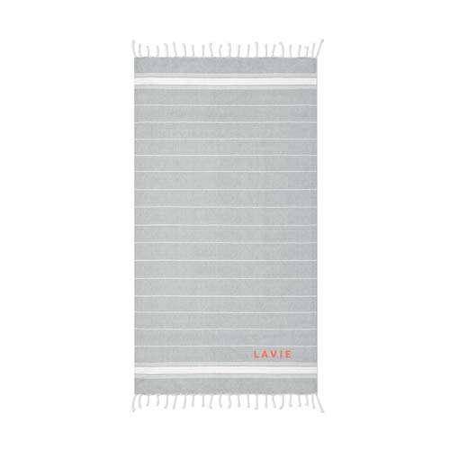 toalla rectangular gris con finas rayas blancas, flecos en los extremos y logo Lavie en naranja