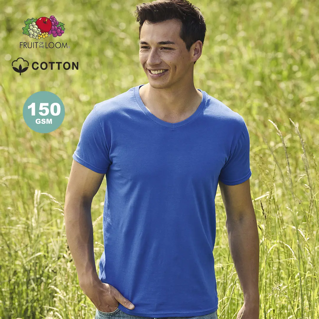 Hombre sonriente con camiseta azul de algodón Fruit of the Loom en un prado verde.