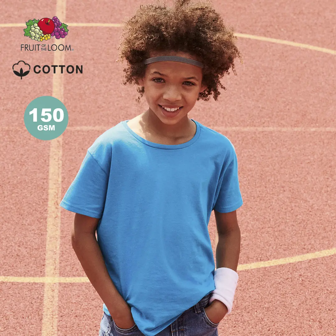 Niño sonriente con camiseta azul de algodón y cinta en la cabeza sobre una pista de atletismo.
