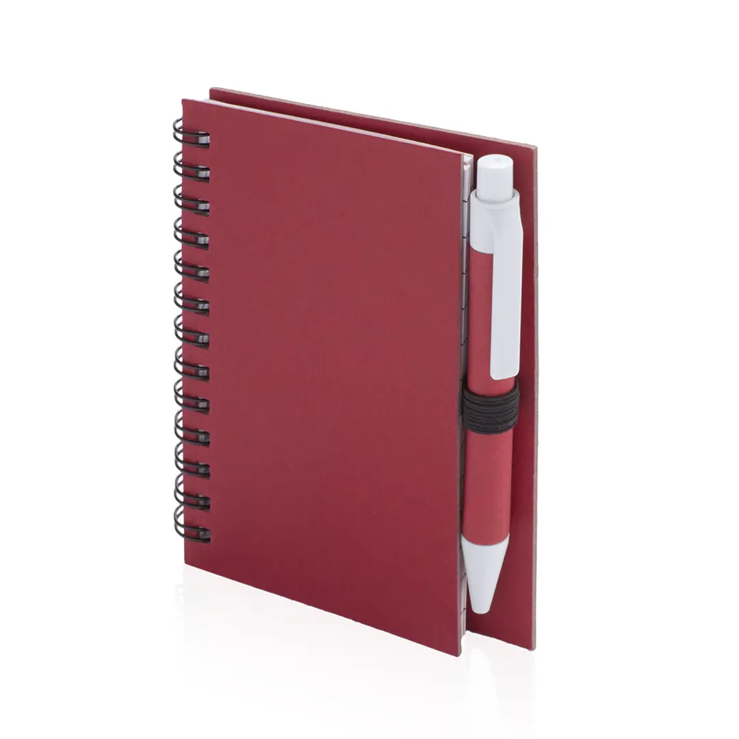 Cuaderno de espiral rojo con bolígrafo sujeto por una goma elasticada al lomo.