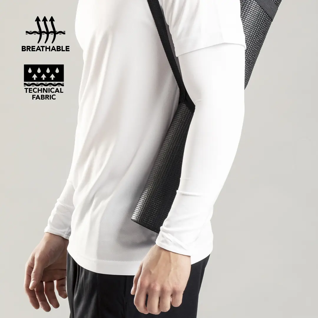 Hombre con camiseta técnica transpirable blanca llevando una esterilla de yoga negra al hombro.