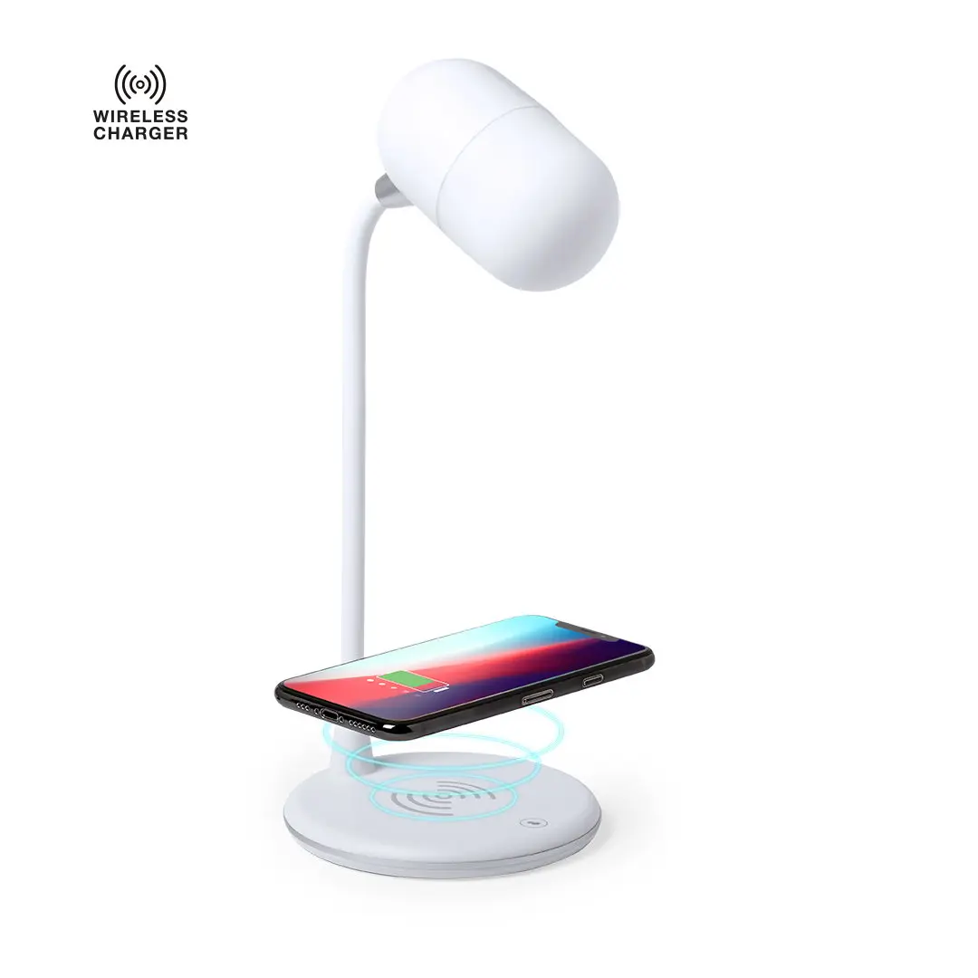 Base de carga inalámbrica de sobremesa con smartphone cargándose bajo lámpara blanca.epam
