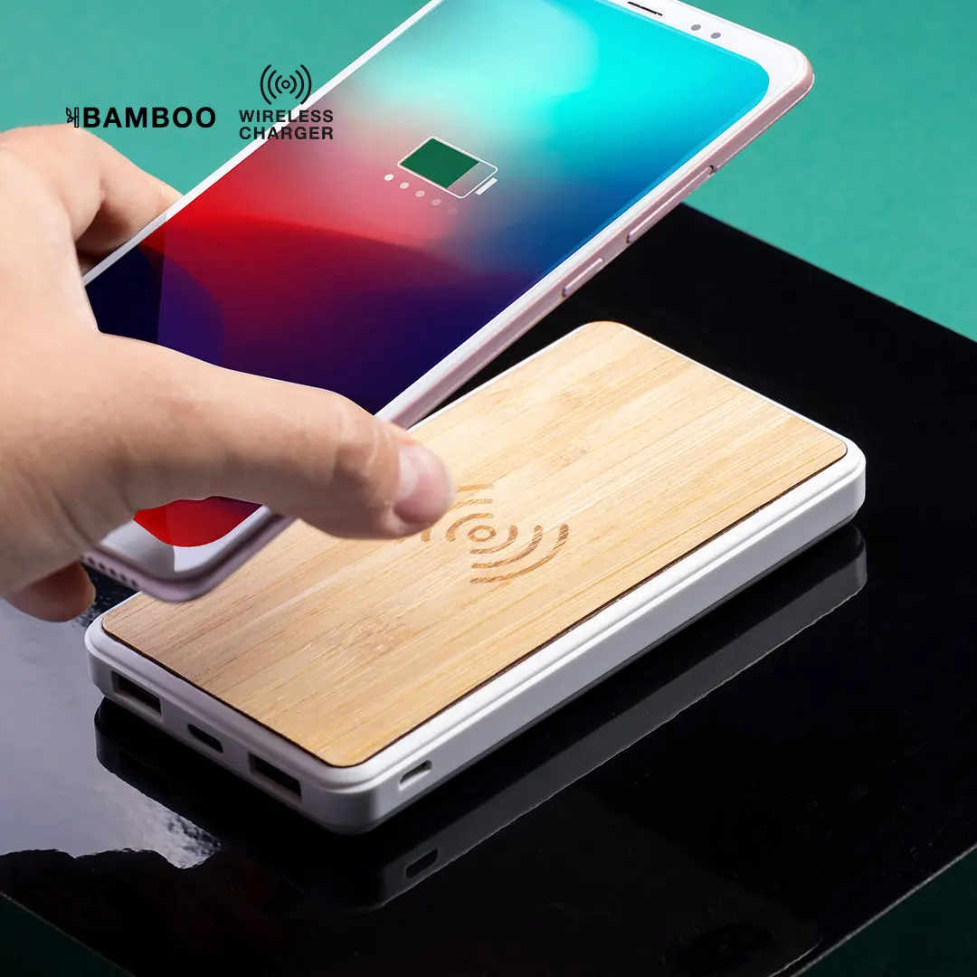 Mano colocando un smartphone sobre una base de carga inalámbrica con superficie de bambú.