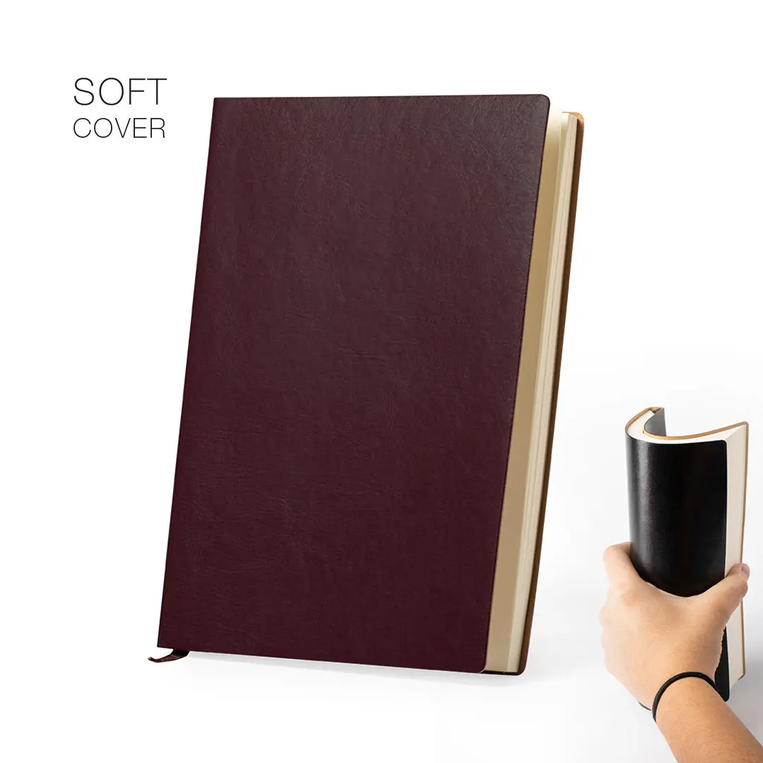 Cuaderno de tapa blanda color granate junto a mano que muestra su flexibilidad al doblar la cubierta negra.
