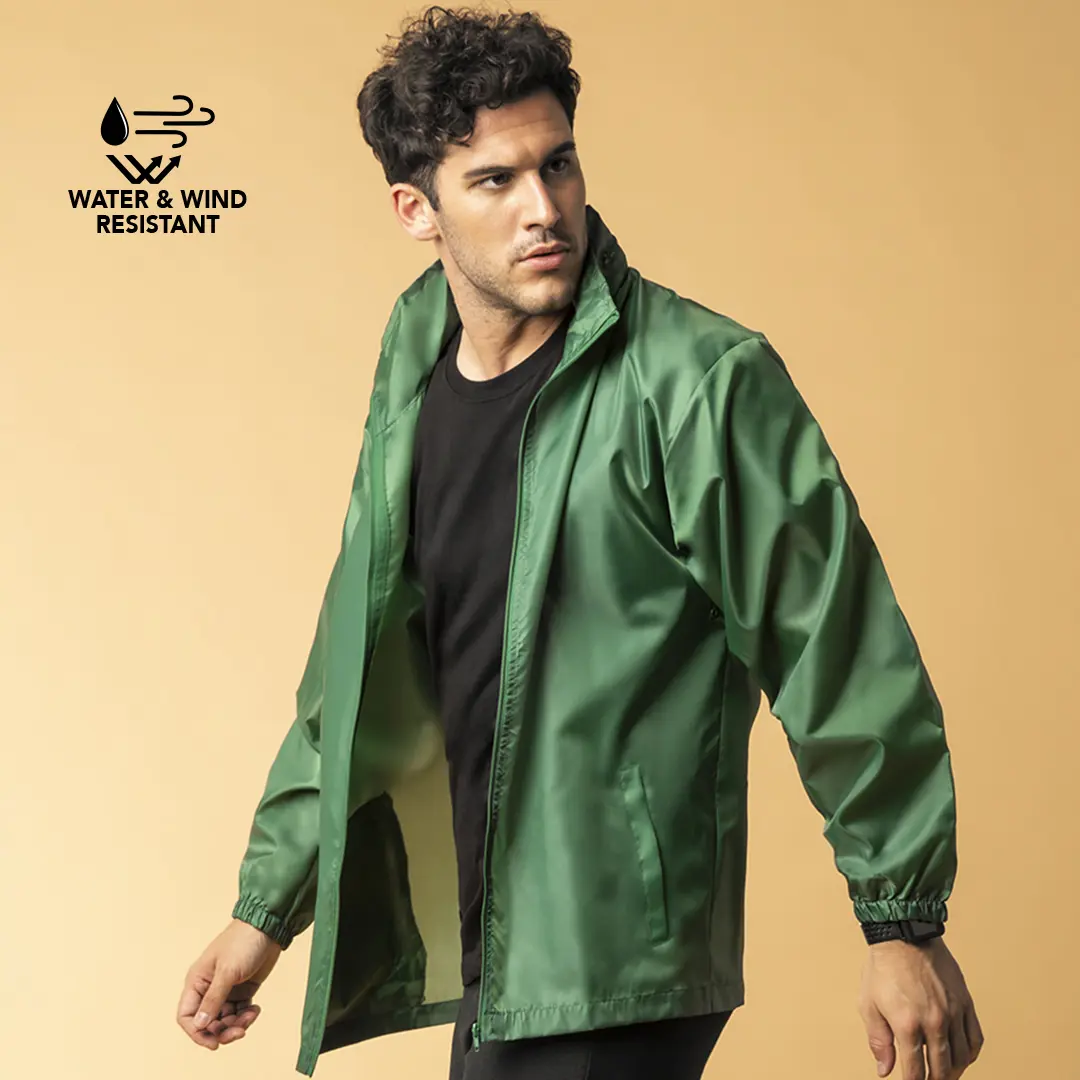 Hombre con chaqueta verde resistente al agua y al viento sobre fondo neutro.
