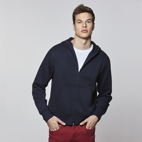Hombre joven con sudadera azul marino y camiseta blanca sobre fondo gris claro