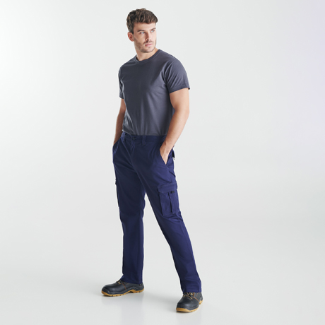 Hombre con pantalones cargo, camiseta básica y zapatos de seguridad sobre fondo blanco