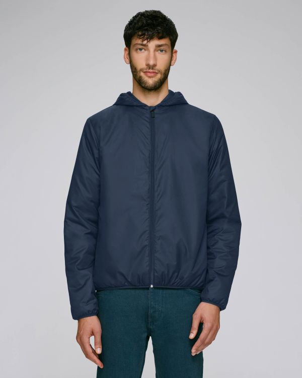 hombre joven de pie con chaqueta acolchada con capucha azul marino sobre fondo neutro