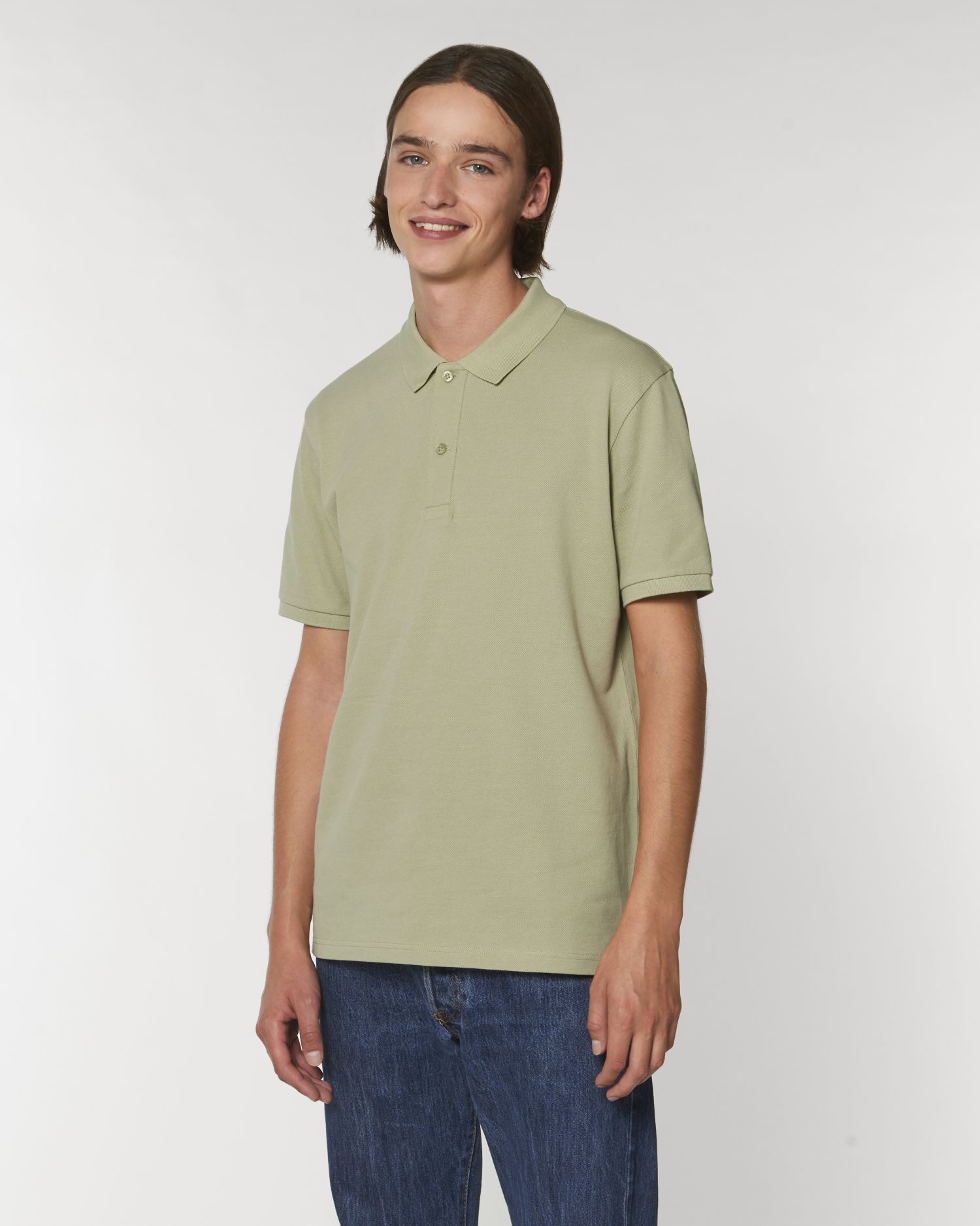 Hombre joven con polo verde claro y vaqueros sobre fondo blanco