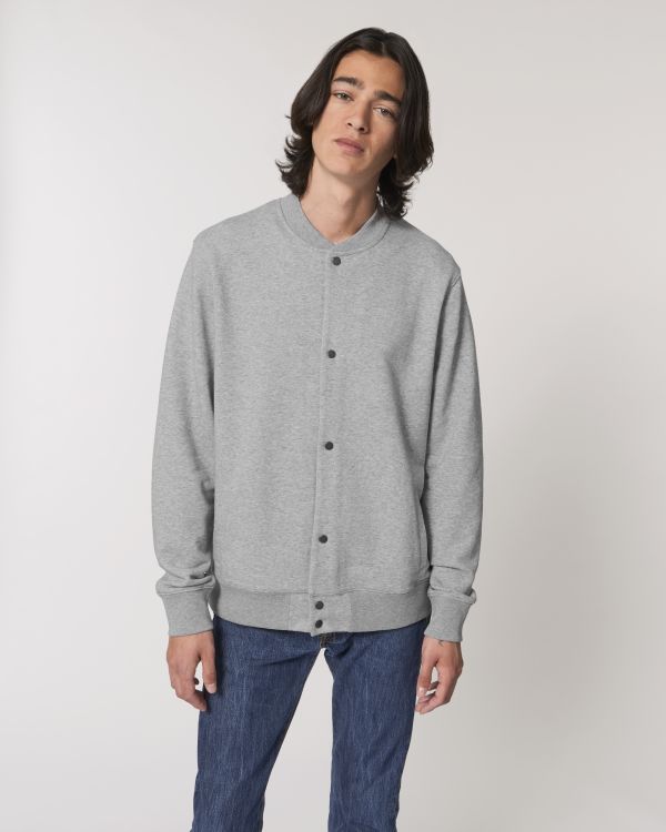 hombre joven con chaqueta tipo bomber gris de botones y vaqueros sobre fondo neutro