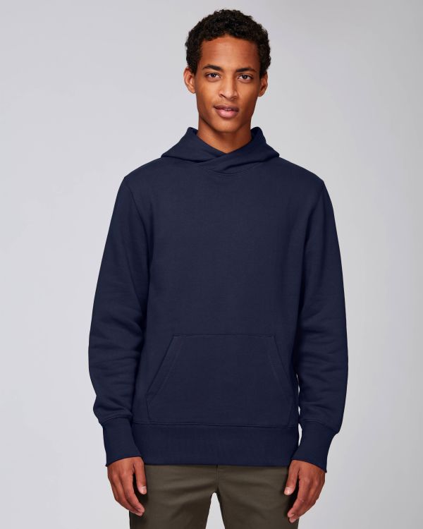 hombre joven de pie con sudadera con capucha azul marino sobre fondo neutro