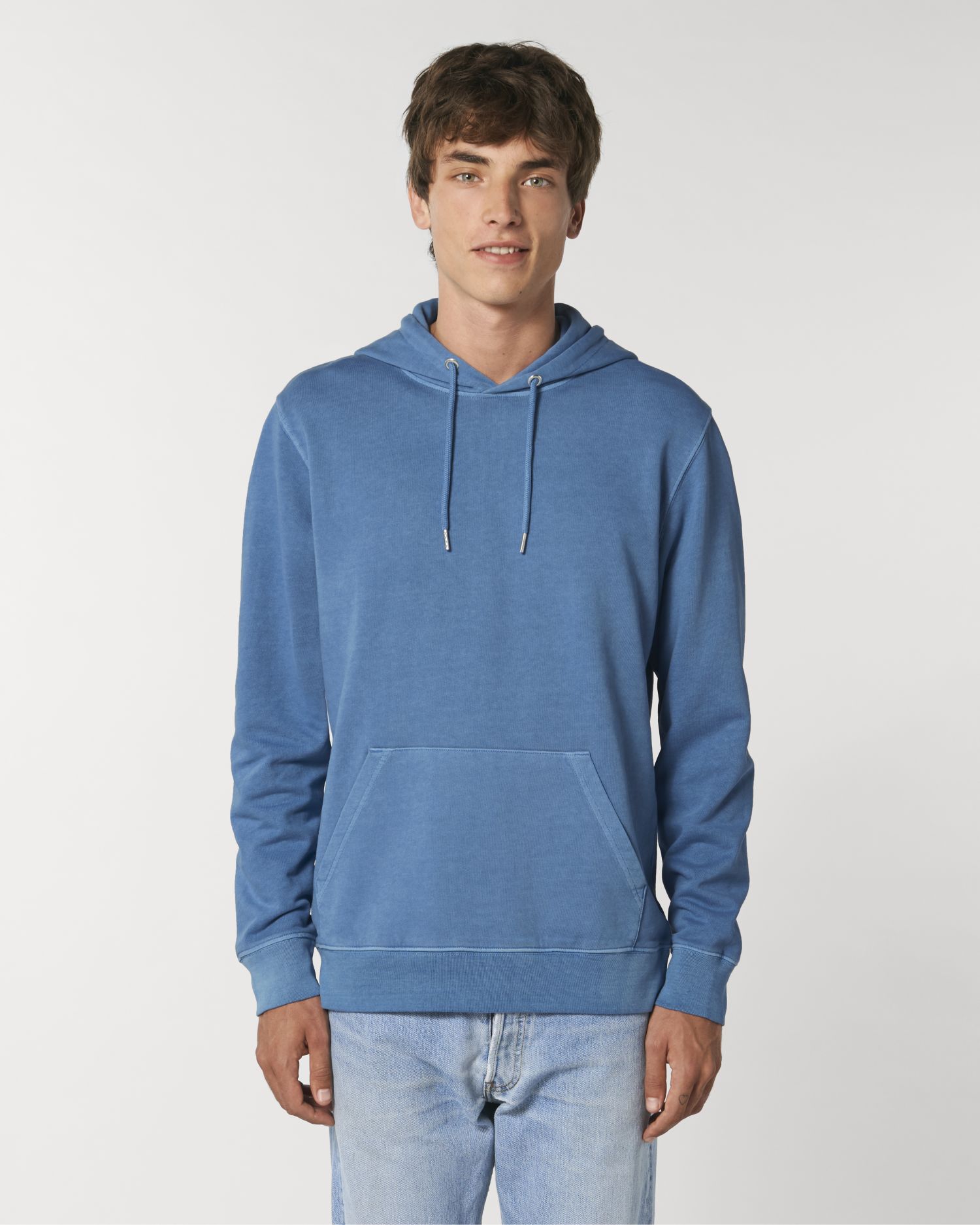 Hombre joven con sudadera con capucha azul y vaqueros sobre fondo blanco