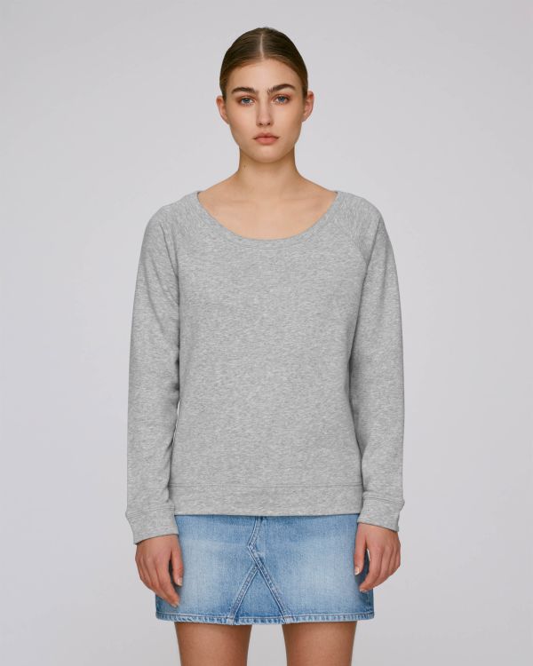 Mujer joven con sudadera gris de manga larga y minifalda vaquera sobre fondo neutro