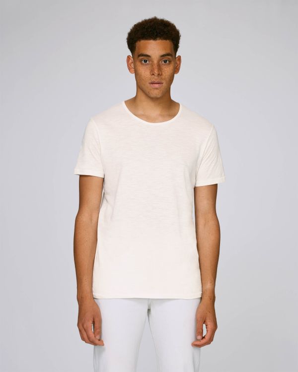 hombre joven con camiseta blanca de manga corta posando sobre fondo neutro claro