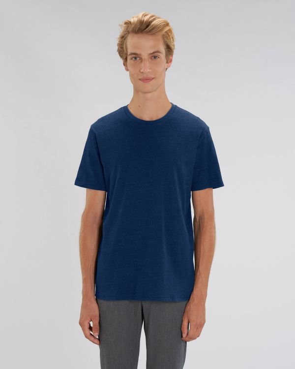 Hombre joven con camiseta azul marino de manga corta y pantalón gris sobre fondo neutro.