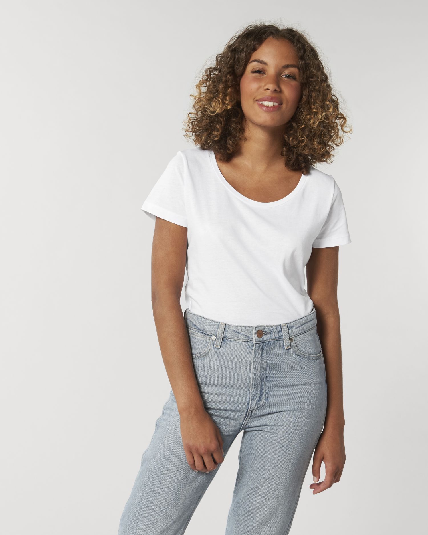Mujer joven con camiseta blanca de manga corta y vaqueros claros sobre fondo neutro