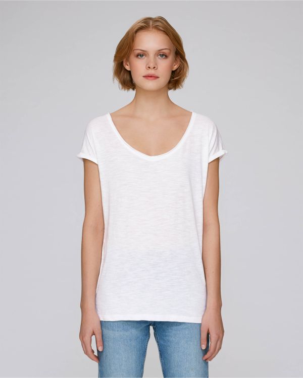 Mujer joven con camiseta blanca de manga corta y vaqueros azules sobre fondo gris.