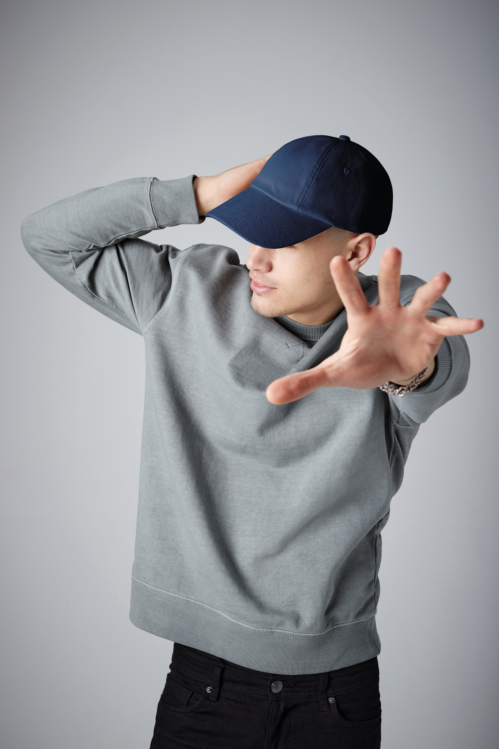 hombre con gorra azul y sudadera gris extendiendo la mano hacia la cámara rechazo intrusión
