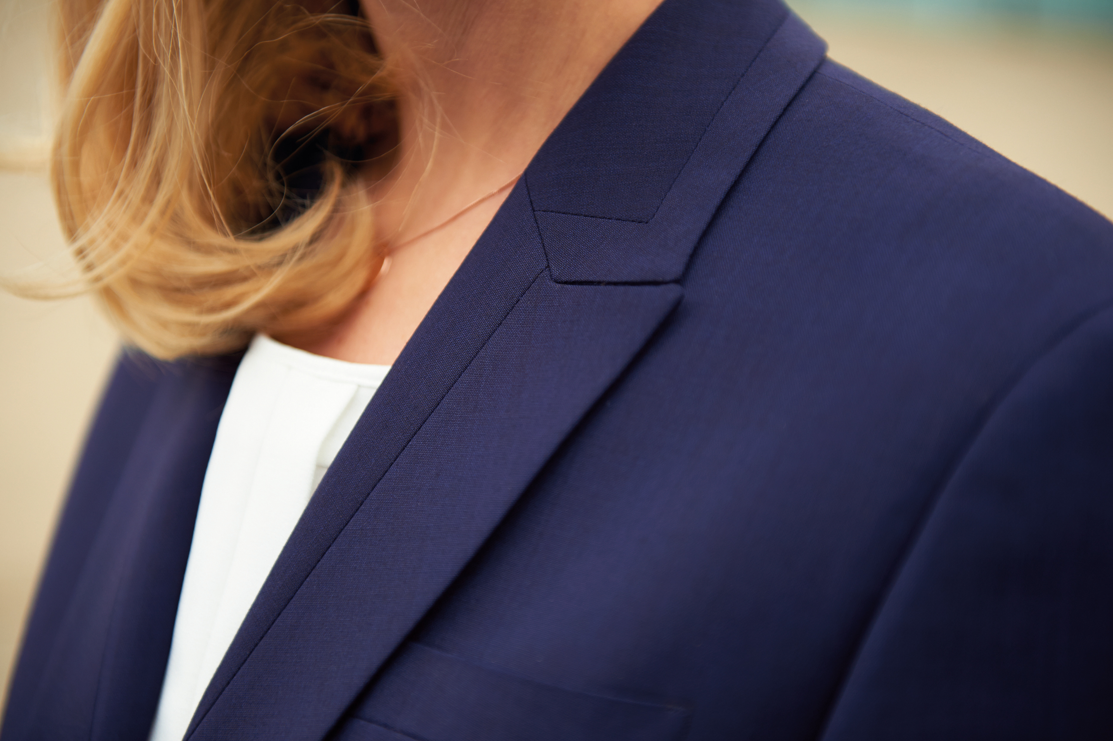 Americana azul marino sobre blusa blanca en primer plano sobre hombro femenino