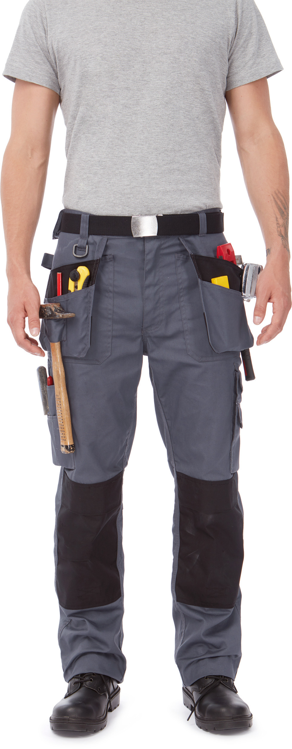 Hombre de pie con pantalones de trabajo grises y cinturón portaherramientas con martillo y útiles en los bolsillos