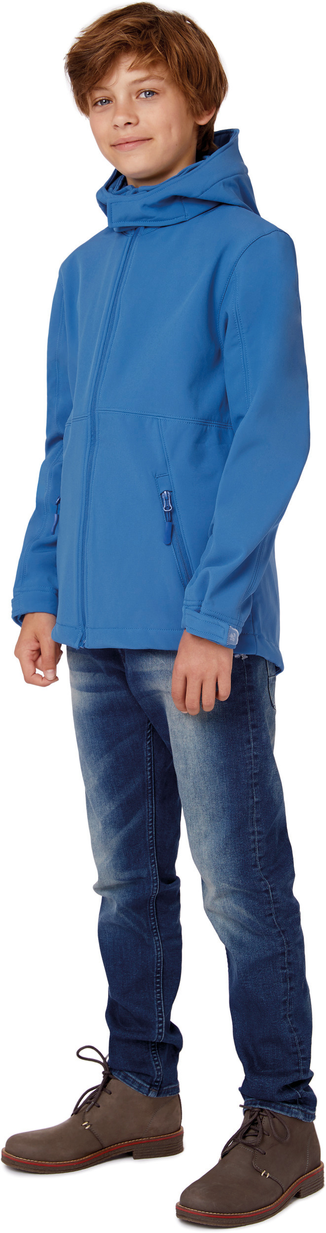 Niño con chaqueta softshell azul con capucha, vaqueros y botas sobre fondo blanco
