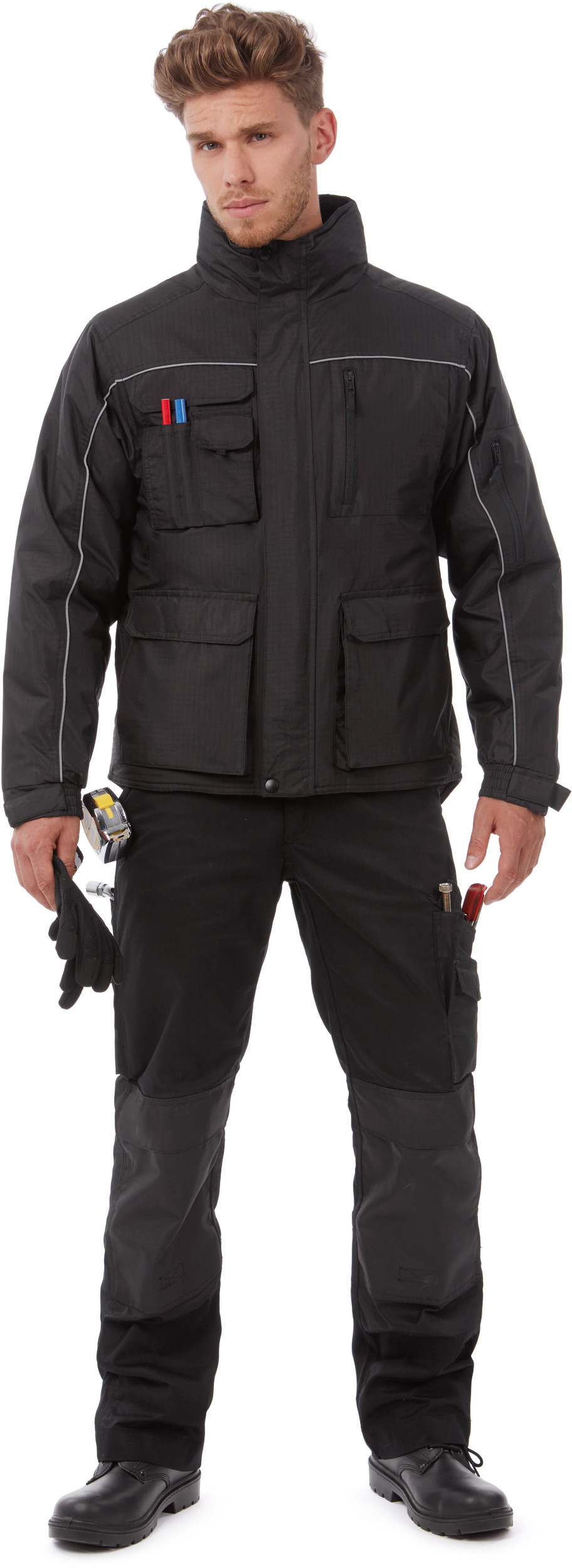 hombre con ropa de trabajo negra y herramientas en bolsillos (cinta métrica, guantes y destornillador)