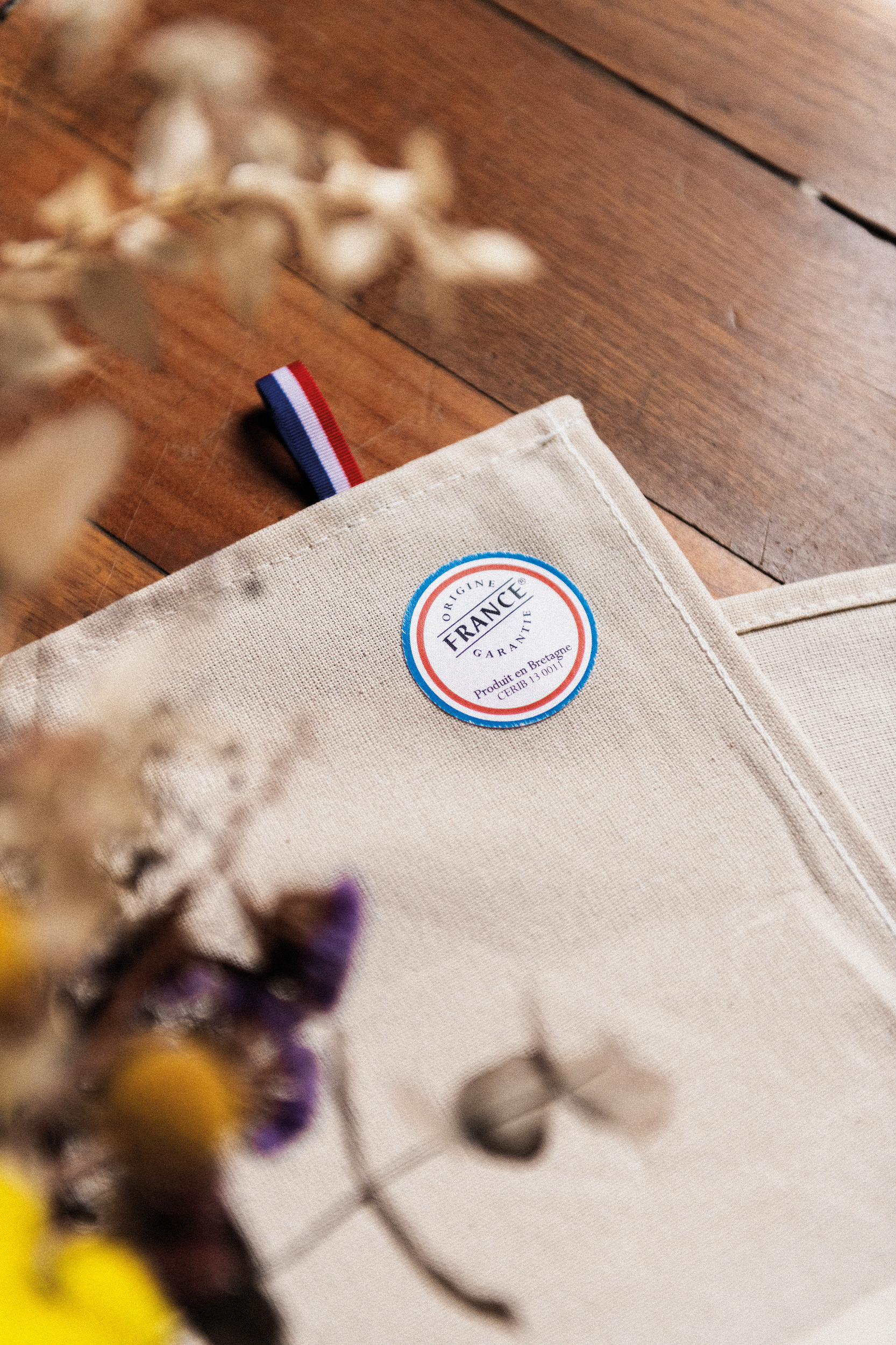 paño de lino claro con etiqueta Origine France Garantie y detalle de cinta tricolor sobre mesa de madera