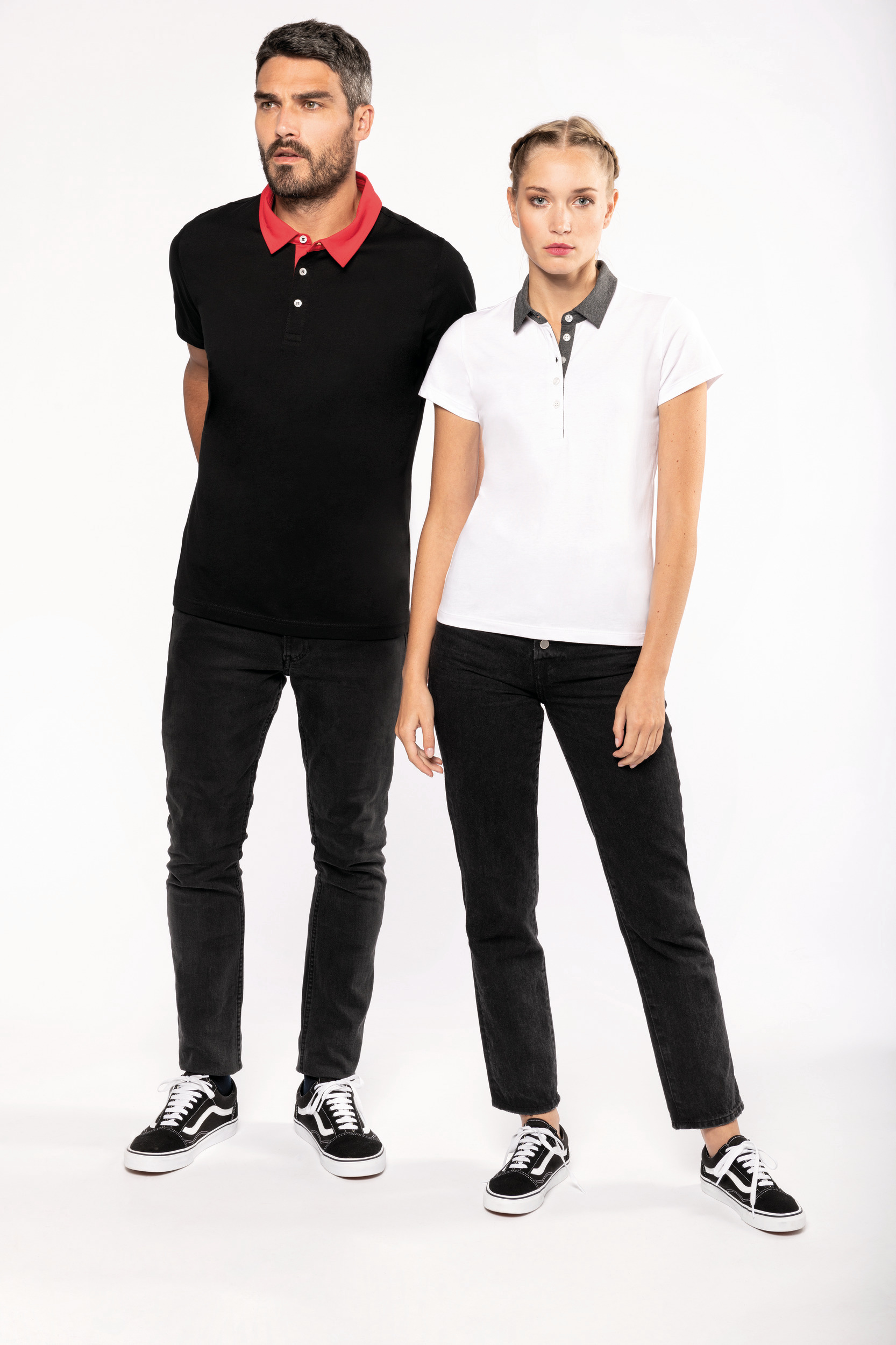 pareja joven de pie con polos blanco y negro, vaqueros y zapatillas Vans sobre fondo blanco