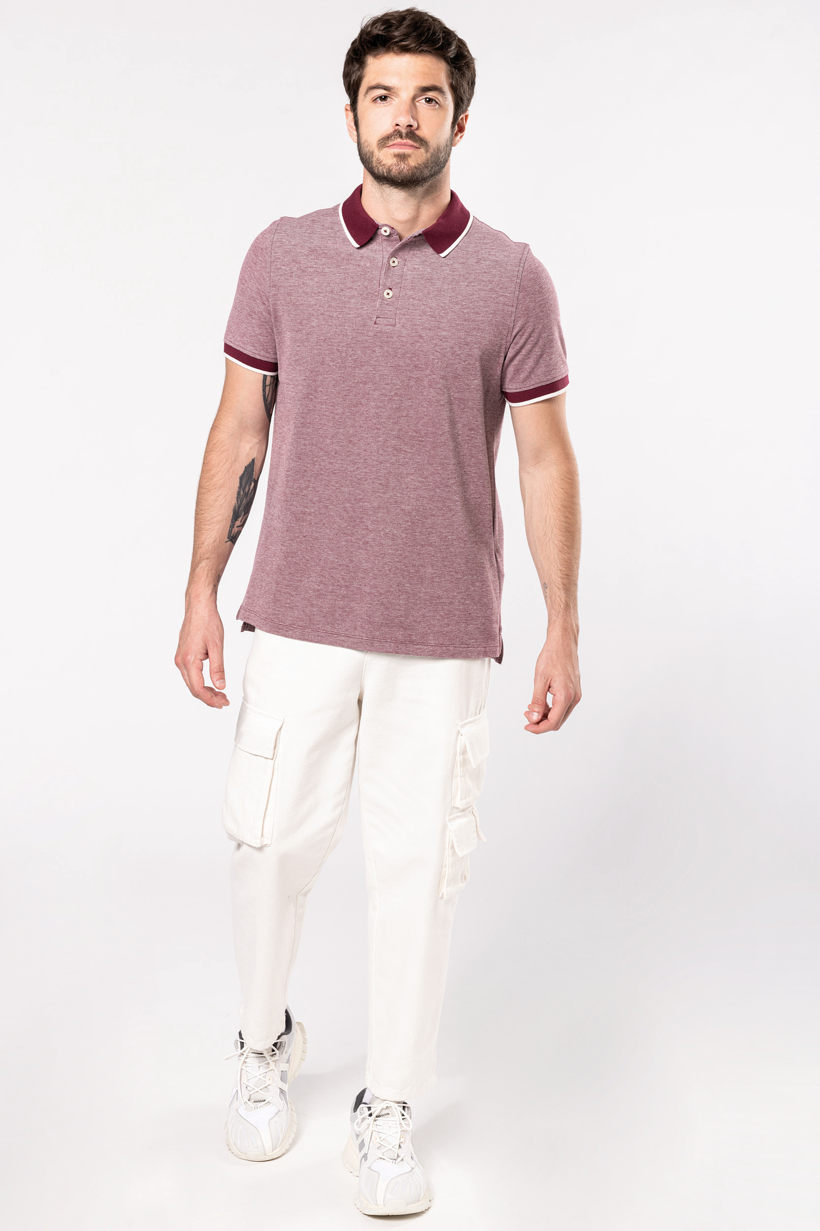 Hombre con polo burdeos de manga corta y pantalones cargo blancos de estilo casual sobre fondo neutro