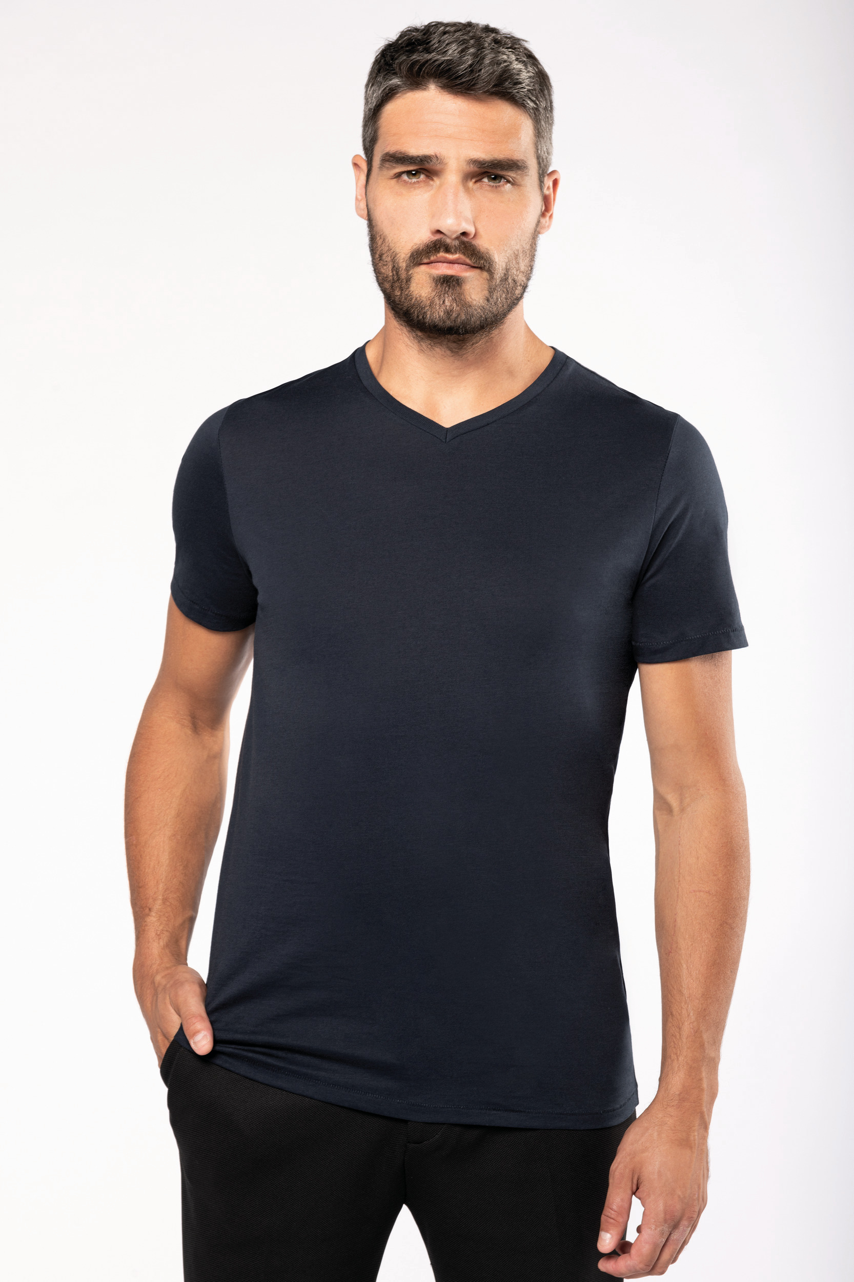 Hombre con camiseta azul marino de cuello en pico sobre fondo blanco sencillo