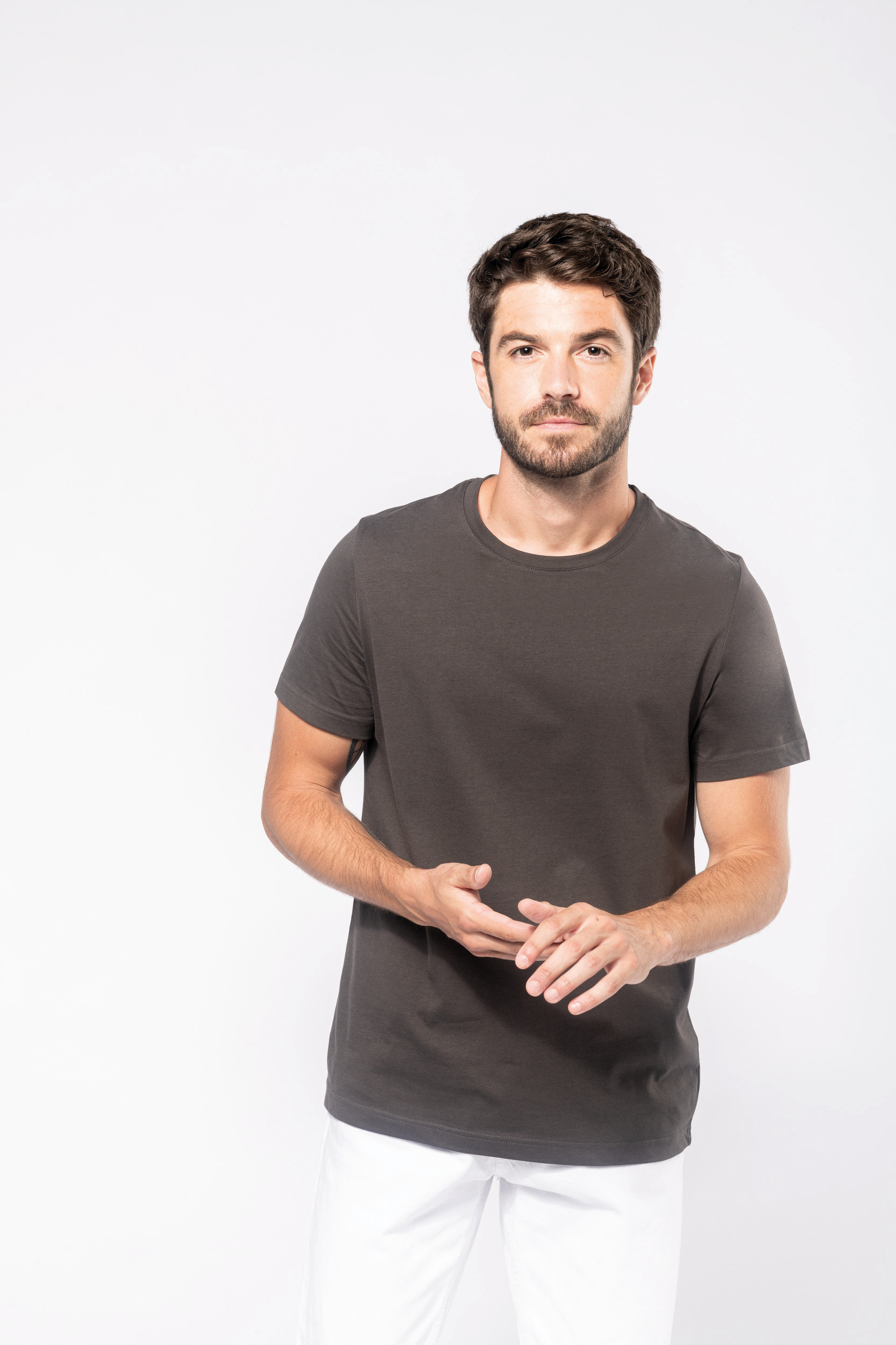 Hombre posando en estudio con camiseta negra de manga corta y pantalones blancos