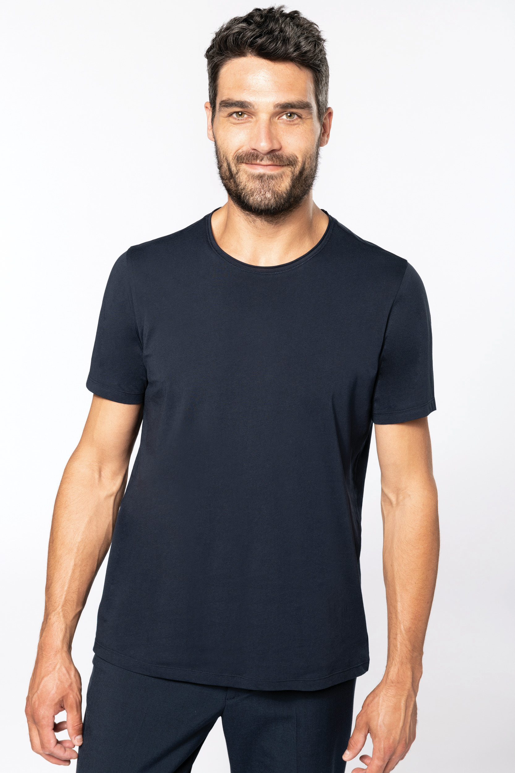 Hombre de pie con camiseta azul marino de manga corta sobre fondo blanco.