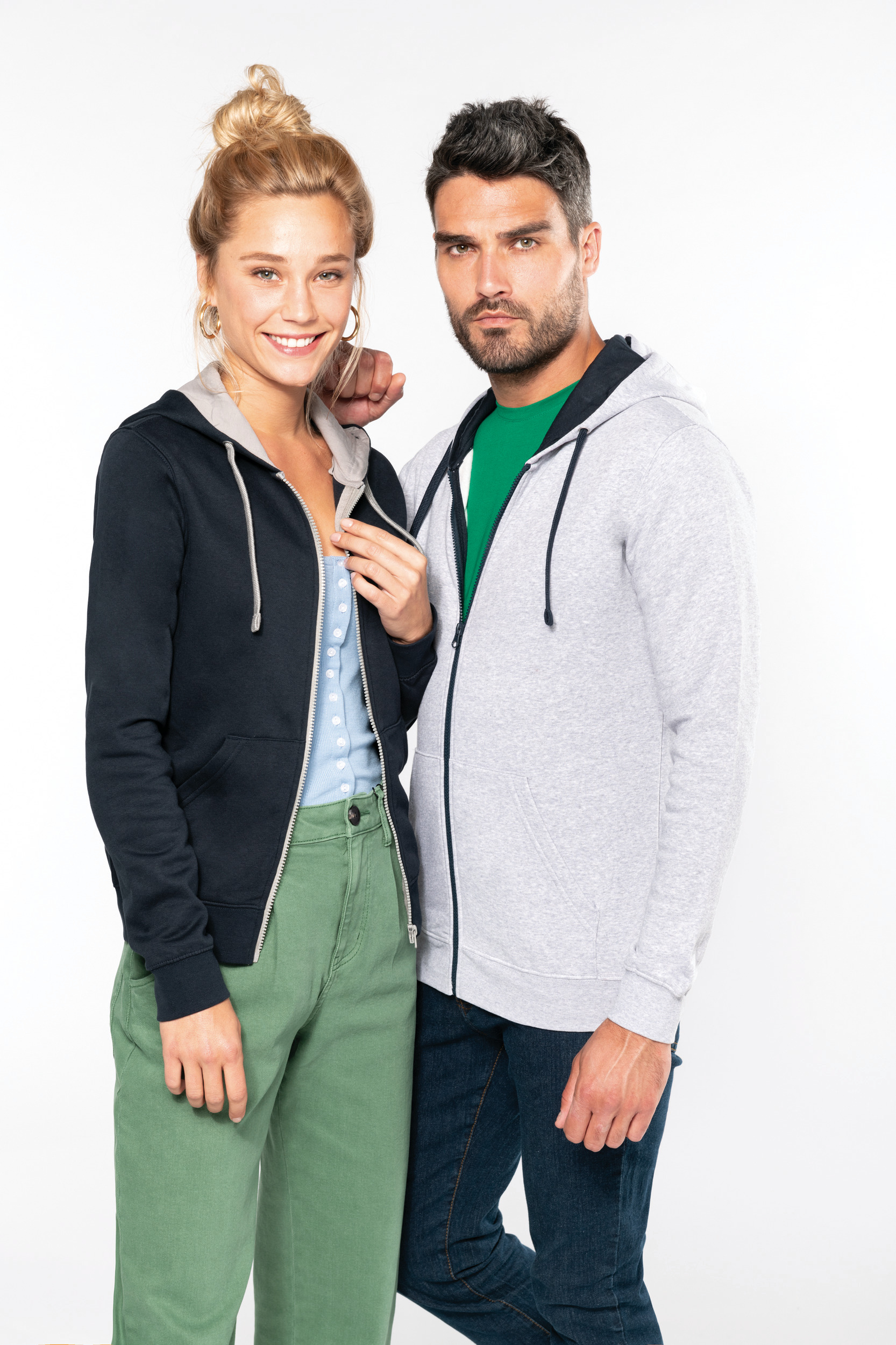 Pareja posando con sudaderas casuales sobre fondo blanco