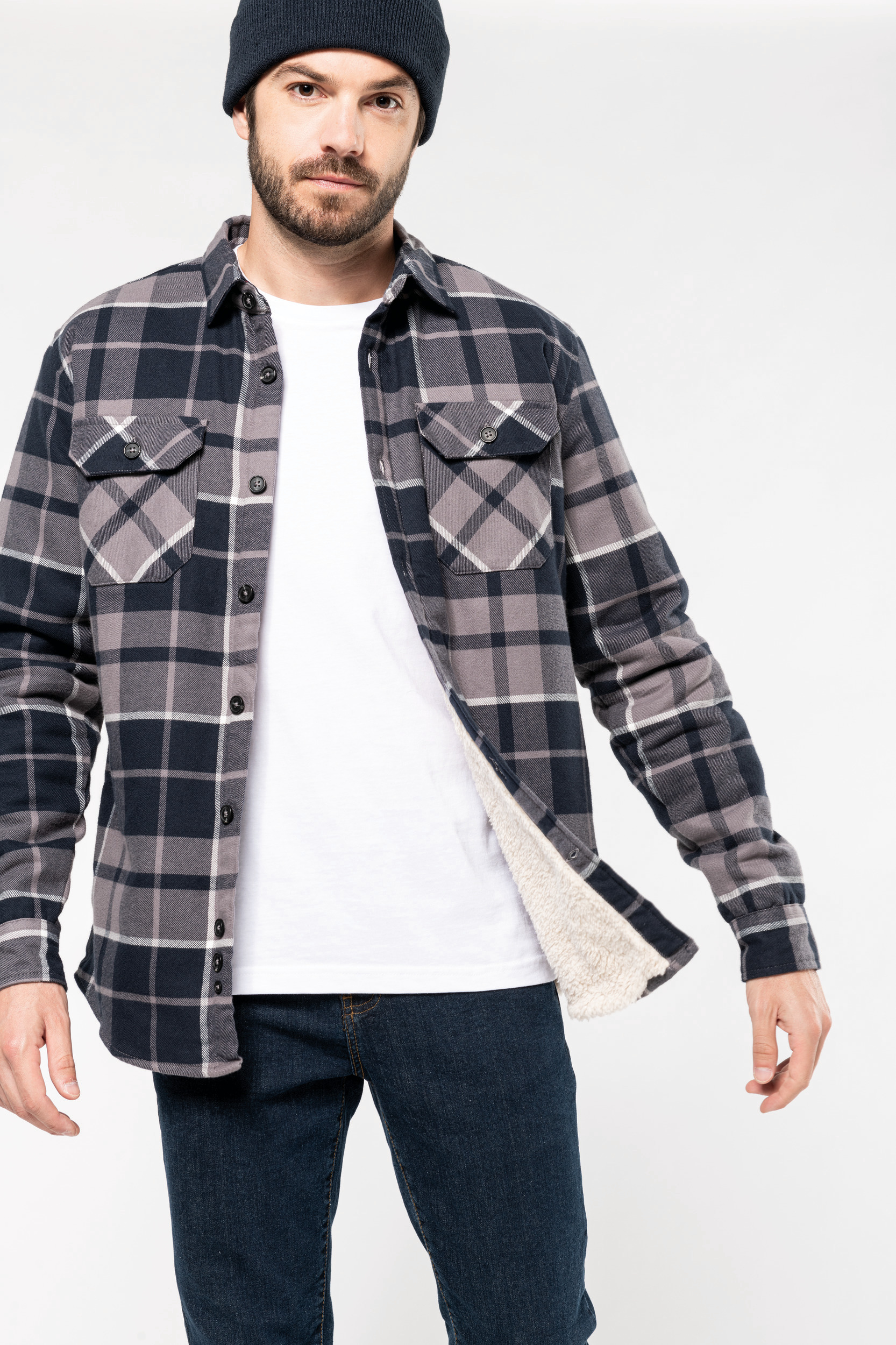 Hombre con gorro y camisa de franela de cuadros forrada sobre camiseta blanca y vaqueros