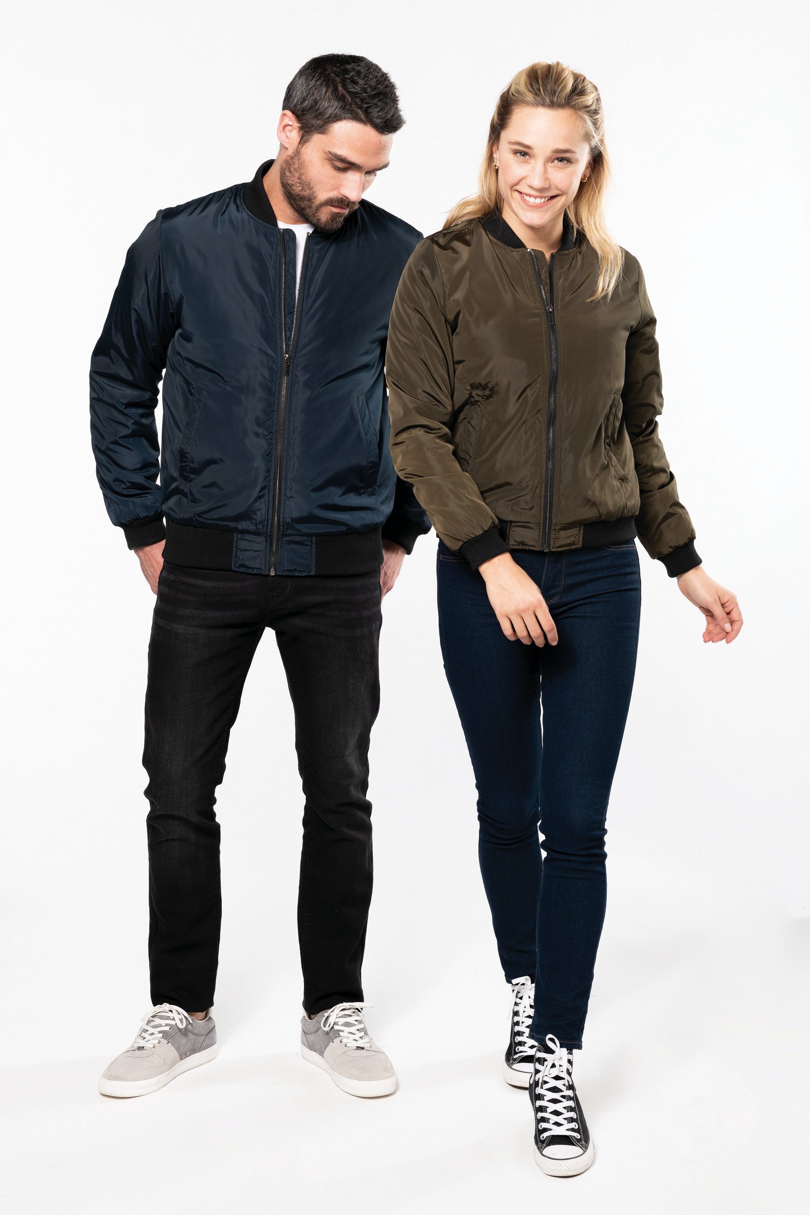 Hombre y mujer caminando con cazadoras bomber en fondo blanco