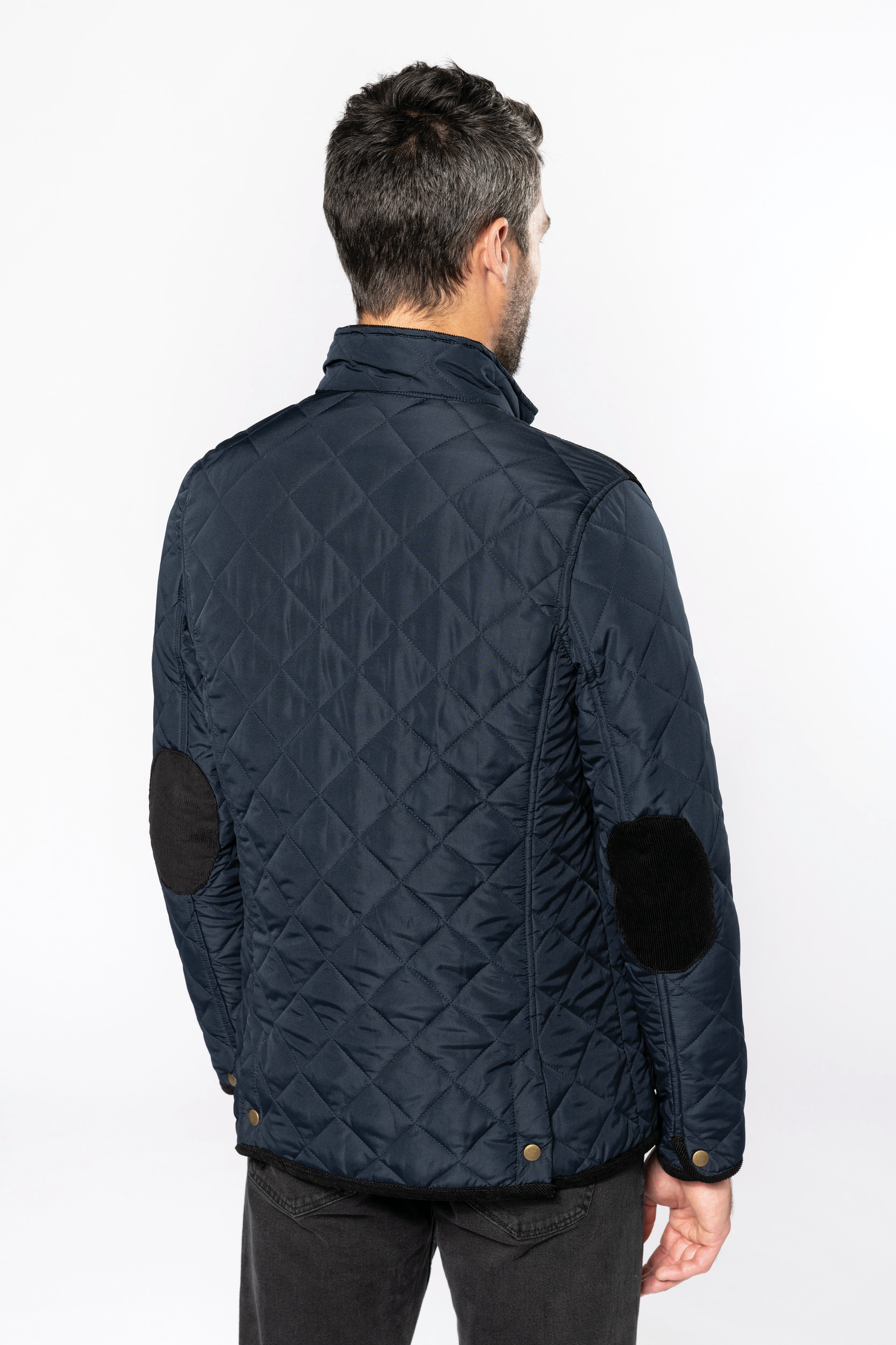 Hombre de espaldas con chaqueta acolchada azul marino y parches negros en los codos