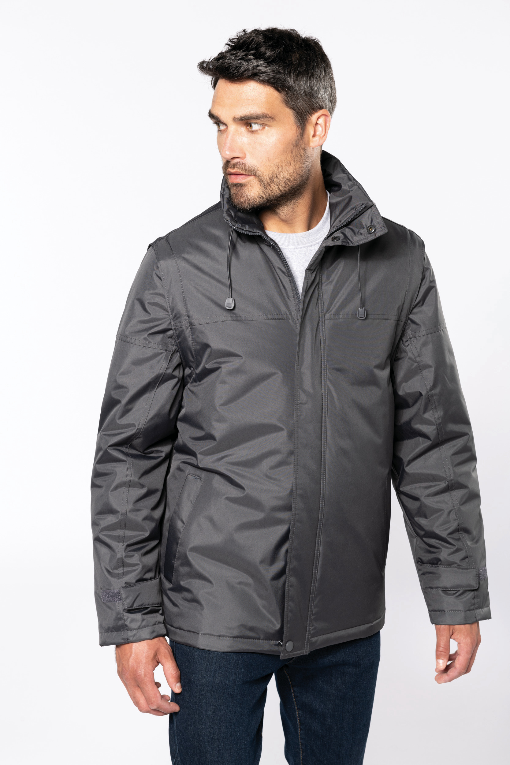 Hombre con chaqueta impermeable gris y vaqueros sobre fondo blanco