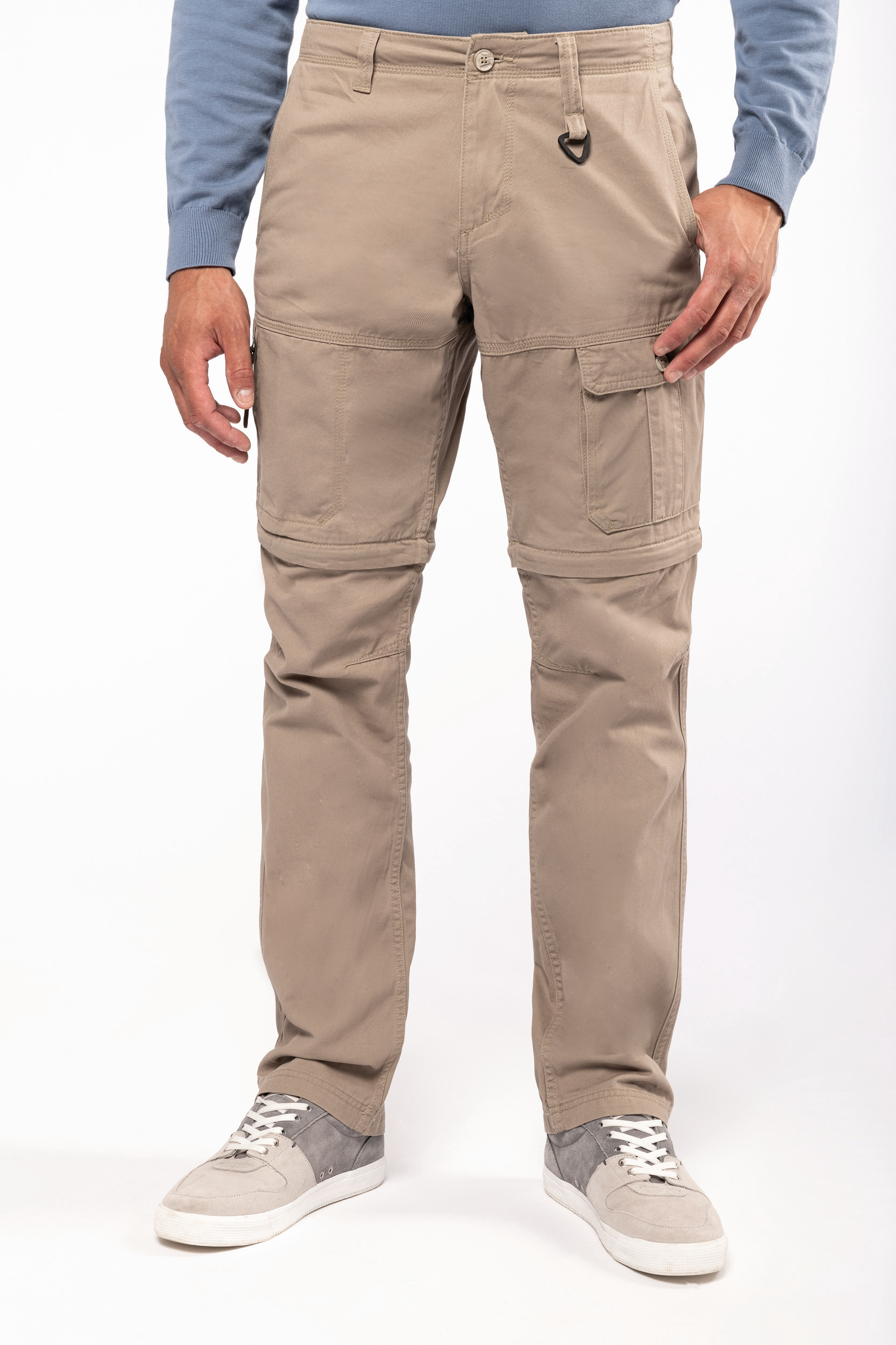 Pantalones cargo beige con cremallera en la rodilla sobre modelo con zapatillas grises