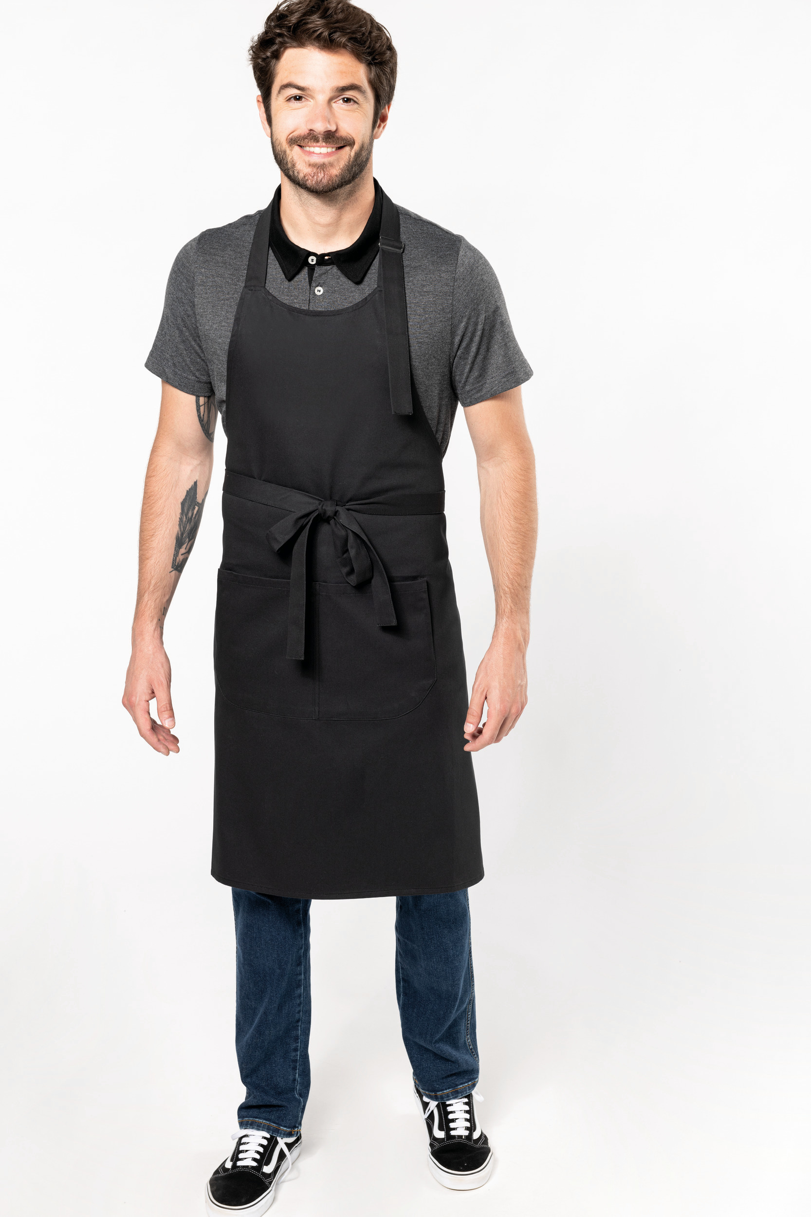 Hombre sonriente con delantal negro sobre camiseta gris de manga corta cinturón atado al frente
