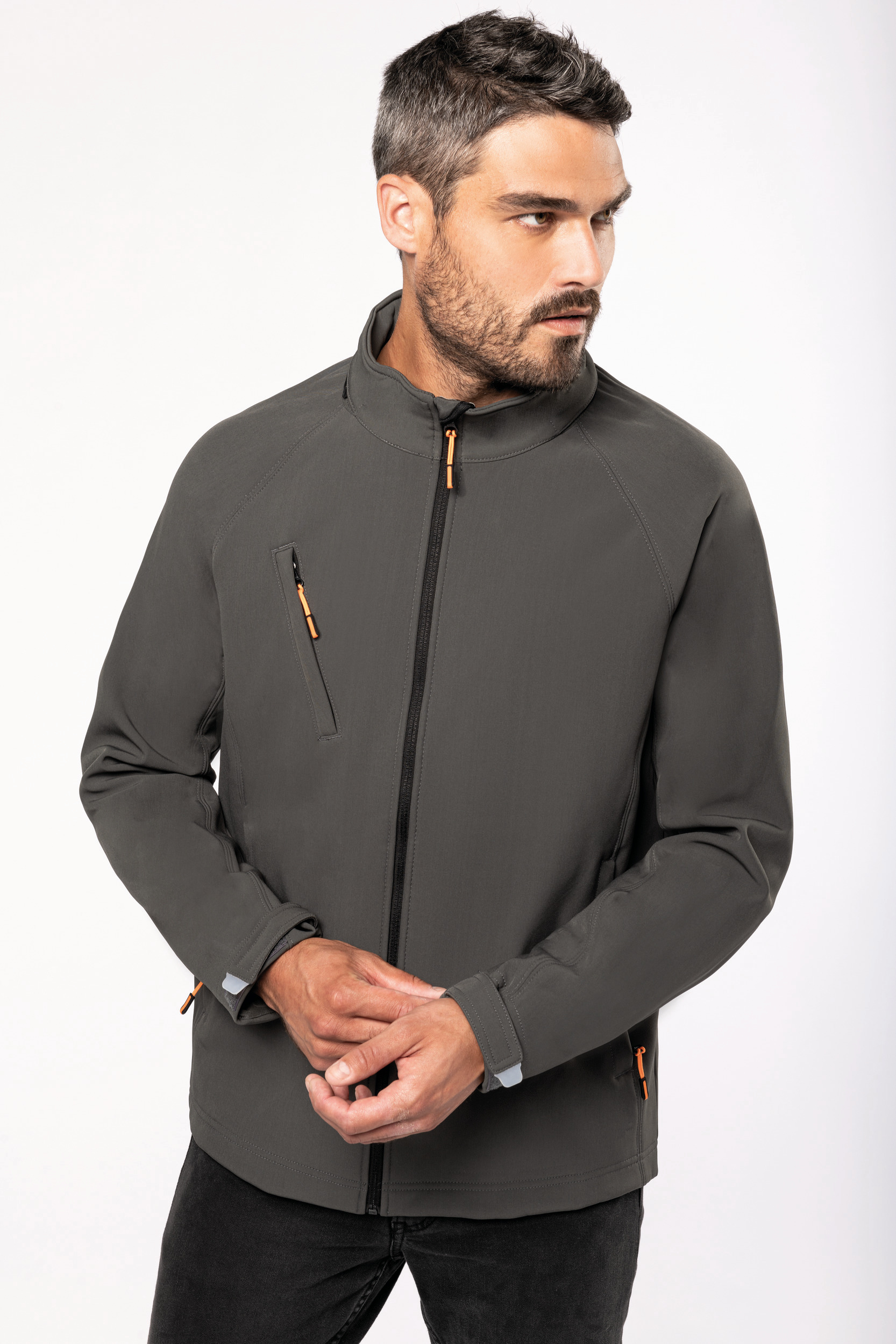 Hombre con chaqueta softshell gris de cremallera frontal mirando hacia un lado
