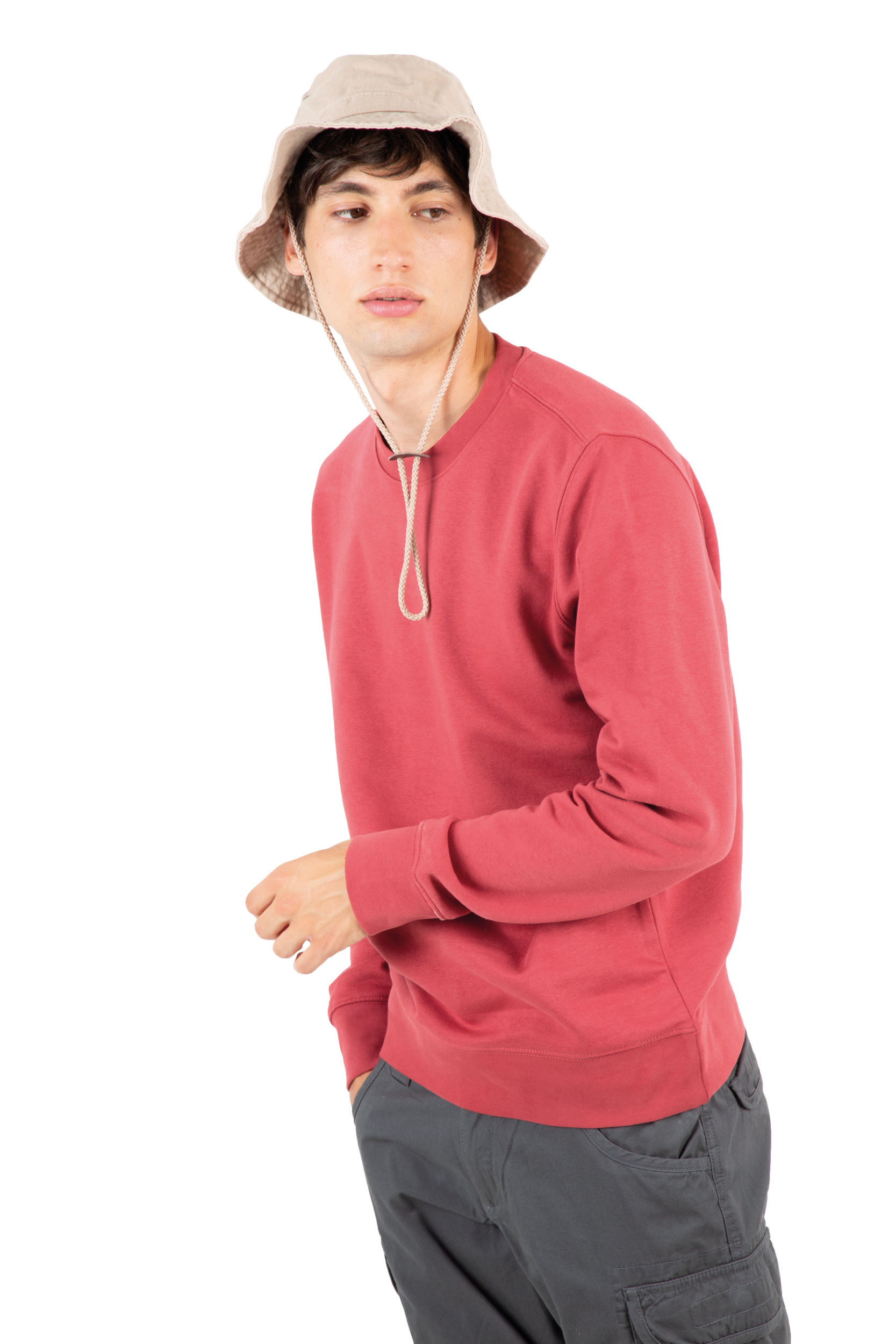 hombre joven con sombrero de pescador y sudadera roja mirando de perfil sobre fondo blanco