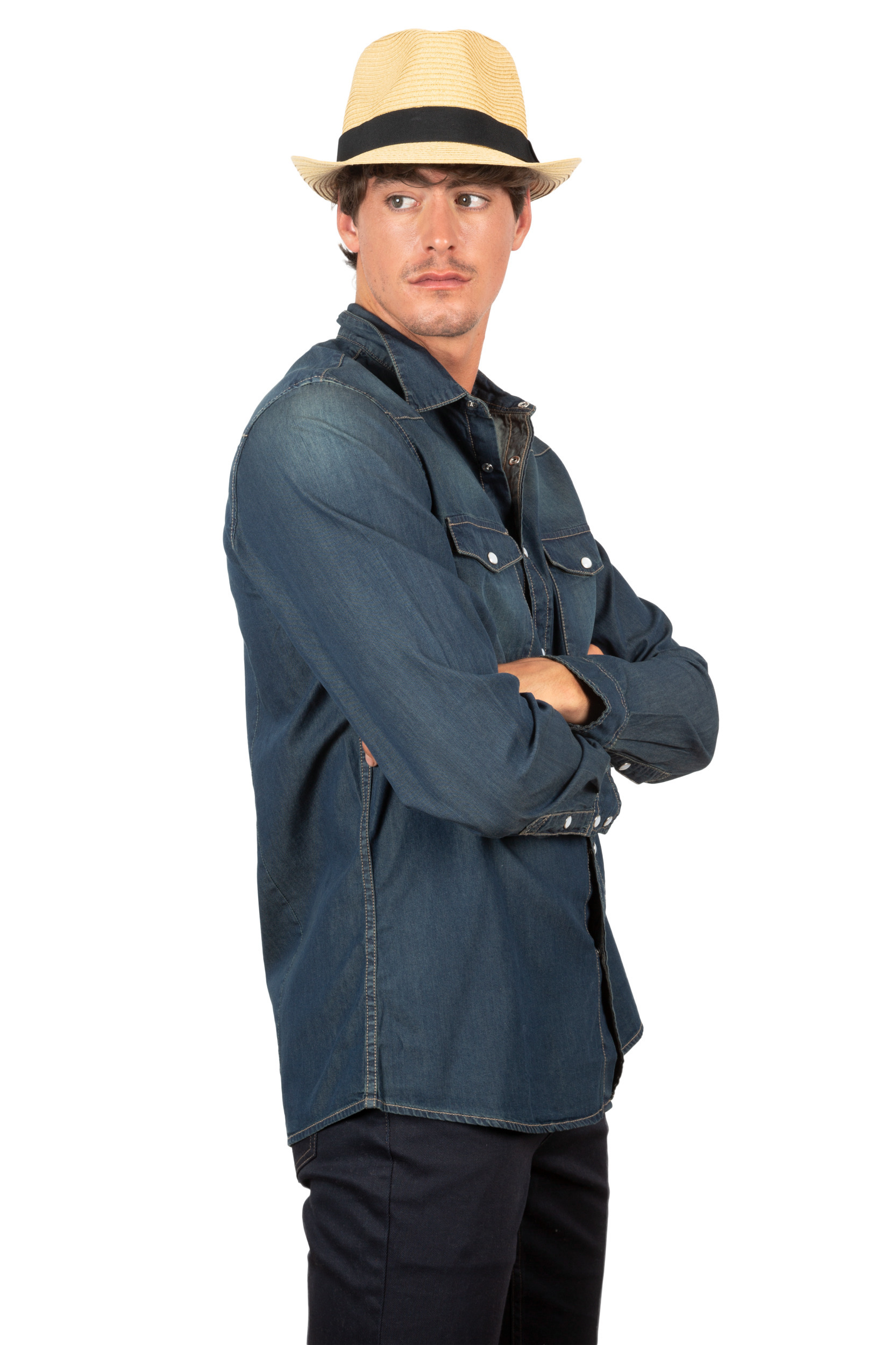 Hombre con sombrero de paja y camisa vaquera de manga larga, brazos cruzados y mirada de perfil sobre fondo blanco