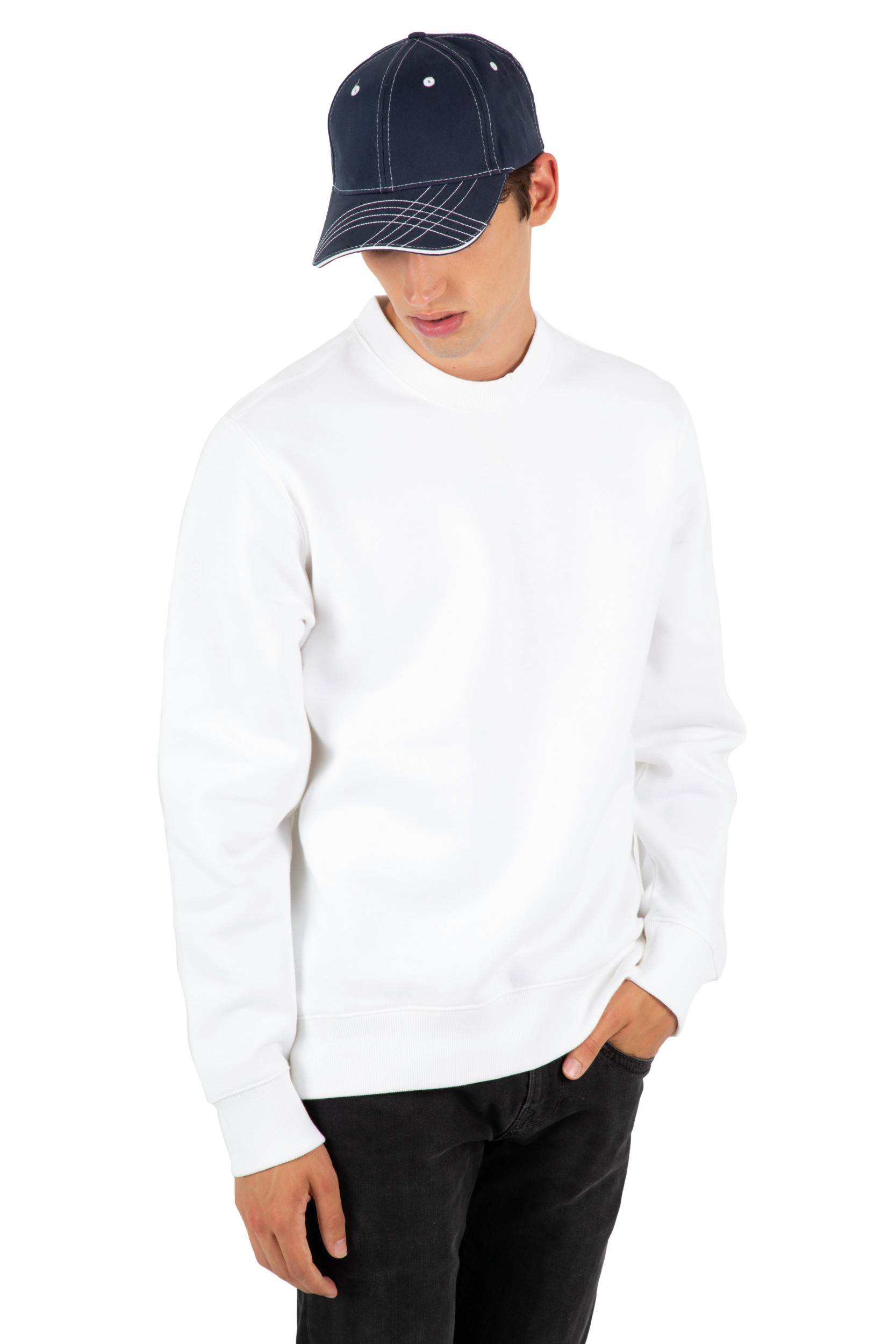 Modelo masculino con sudadera blanca, vaqueros negros y gorra azul marino sobre fondo blanco