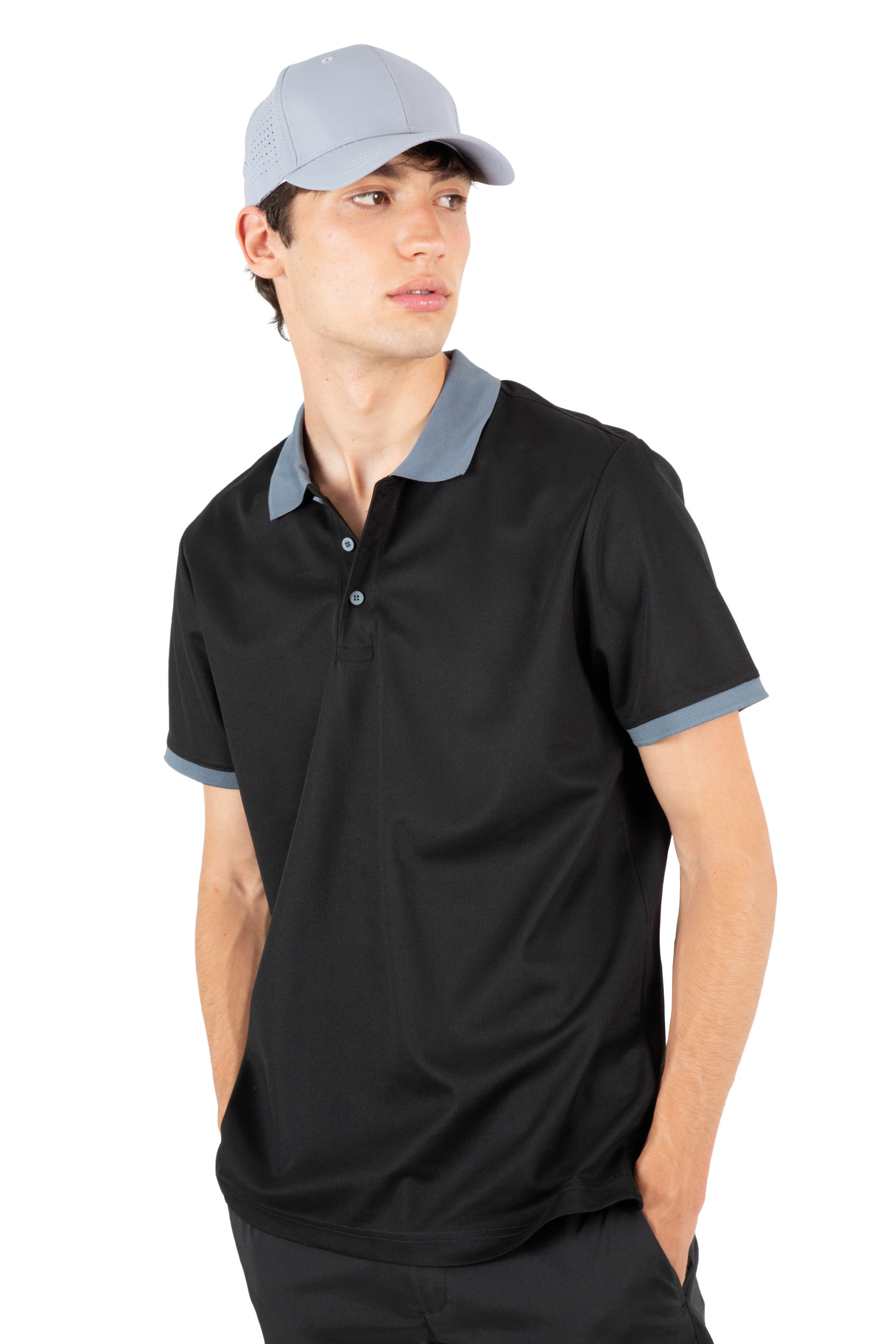 Hombre joven con gorra gris y polo negro con cuello y puños en gris sobre fondo blanco