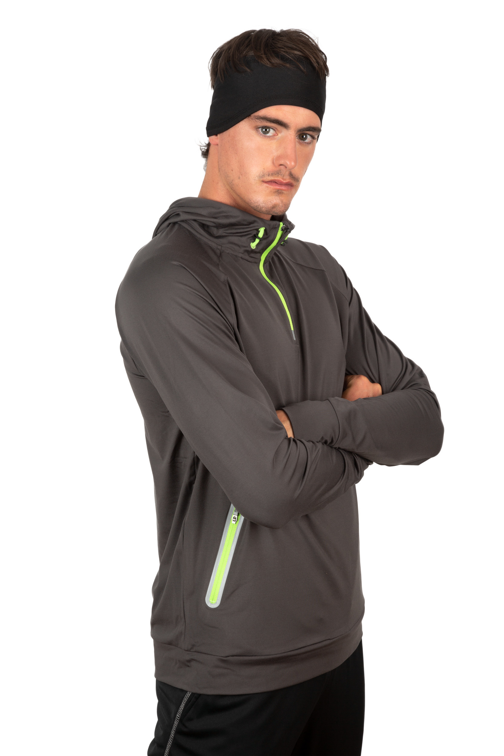 Hombre con sudadera técnica gris y cremallera verde en fondo blanco, cruzado de brazos y con cinta para la cabeza negra.