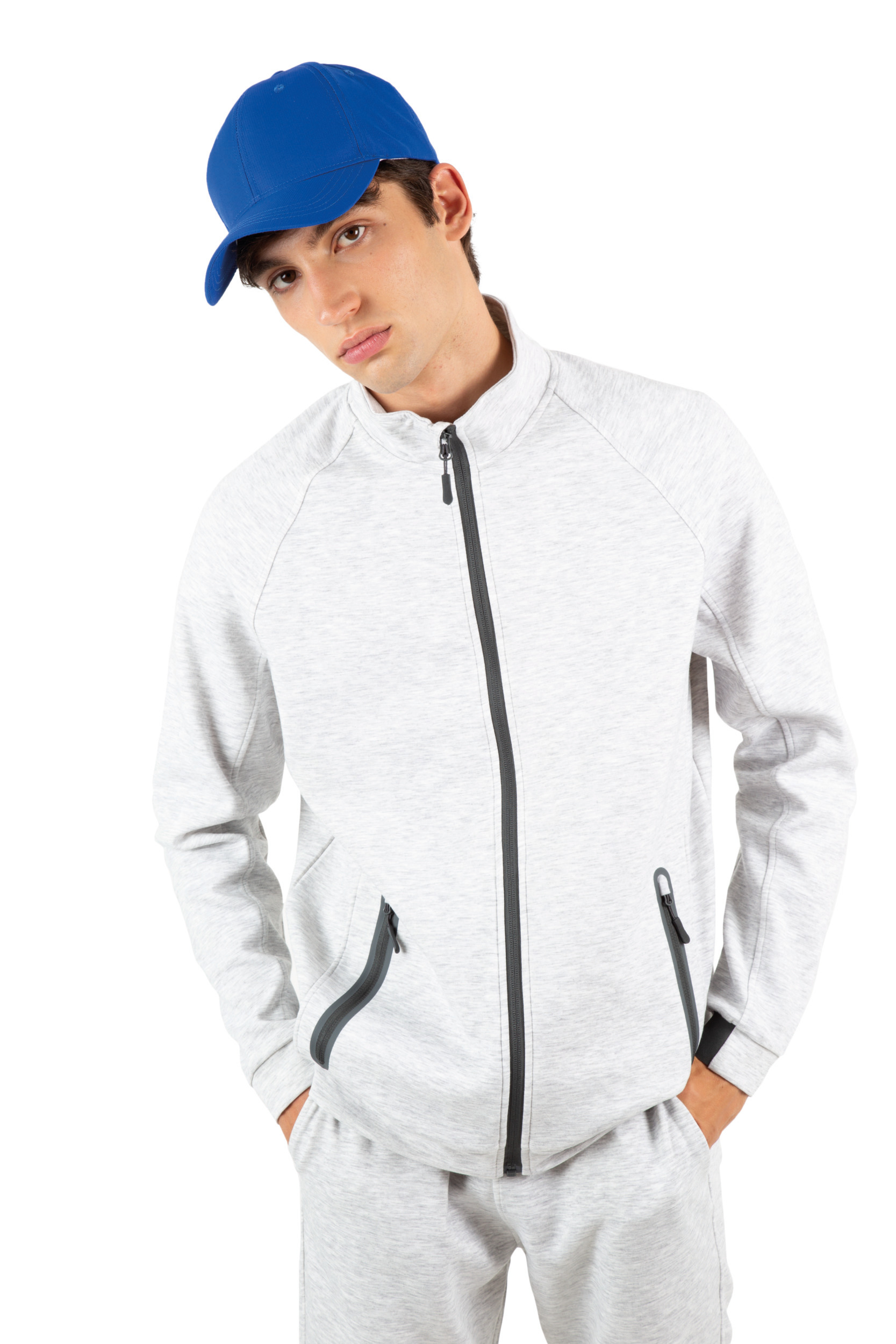 Hombre con chándal gris de cremallera y gorra azul sobre fondo blanco