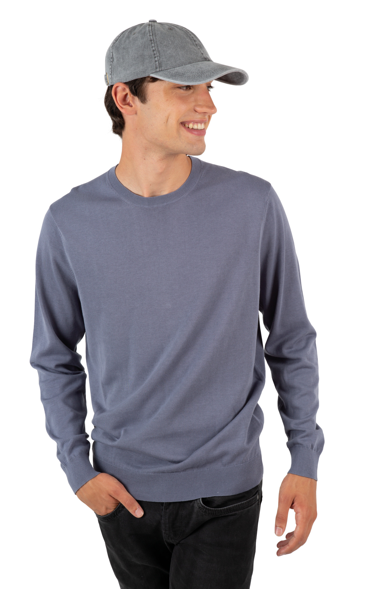 Hombre sonriente con gorra gris y jersey azul claro sobre fondo blanco.