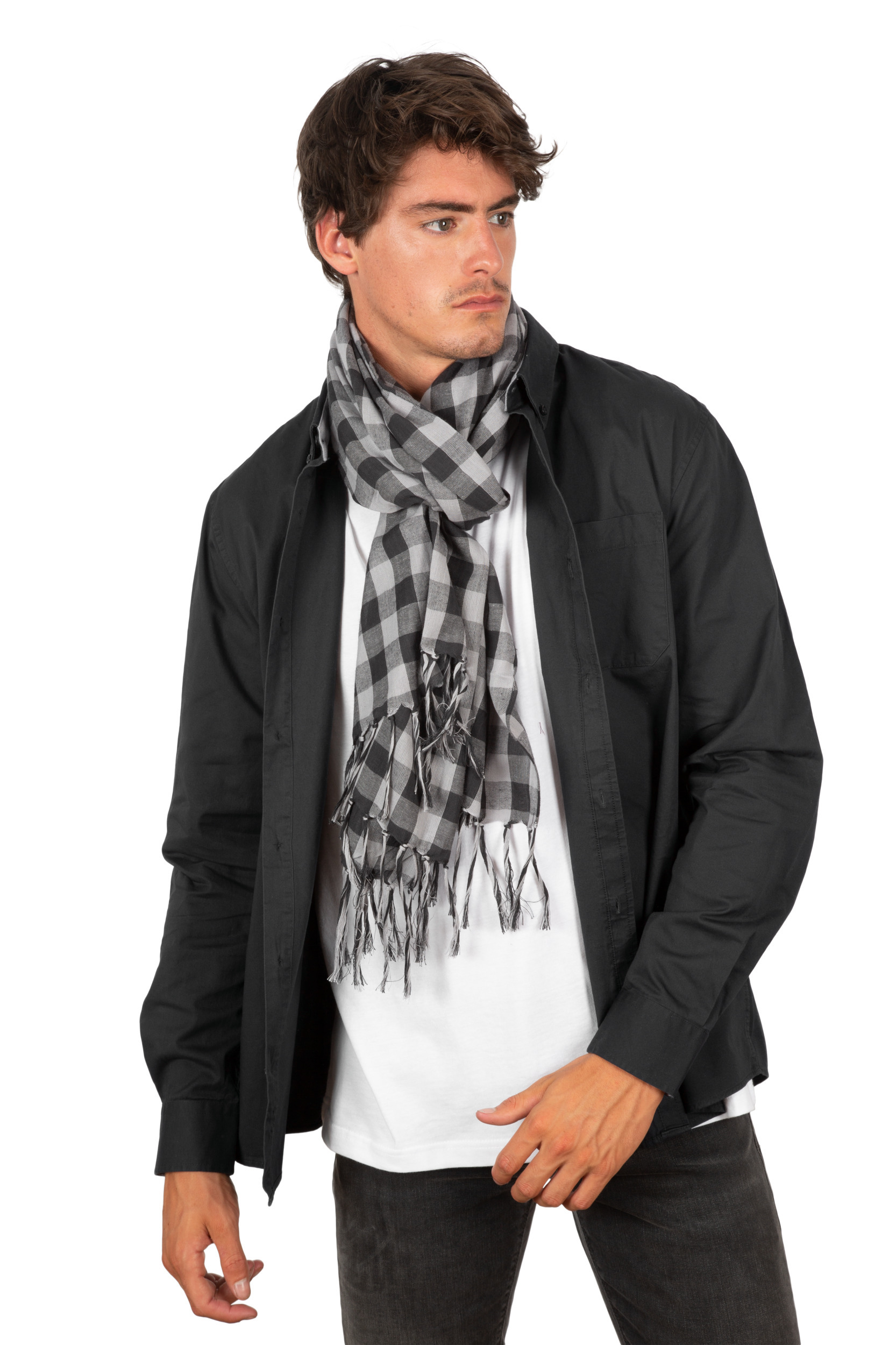 hombre joven con bufanda de cuadros grises, camisa negra abierta y camiseta blanca sobre fondo blanco